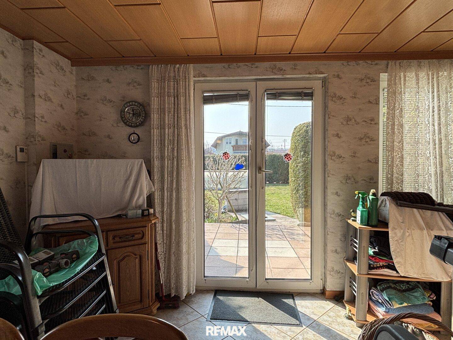 Heller Raum mit Terrassenzugang, Fliesenboden und Blick in den gepflegten Garten.