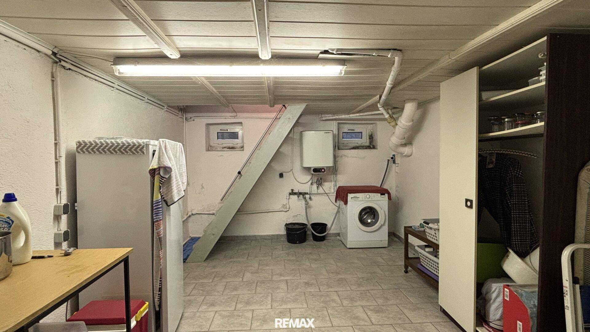 Funktionaler Kellerraum mit Waschmaschine, Warmwasserboiler und Stauraum.
