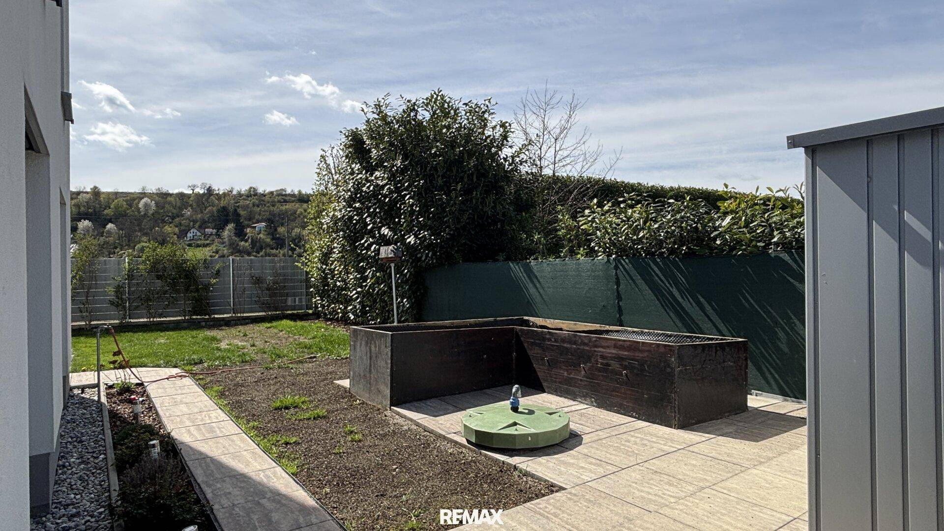 Gartenbereich mit Hochbeeten für den Anbau von Pflanzen und einem praktischen Gartenschuppen.