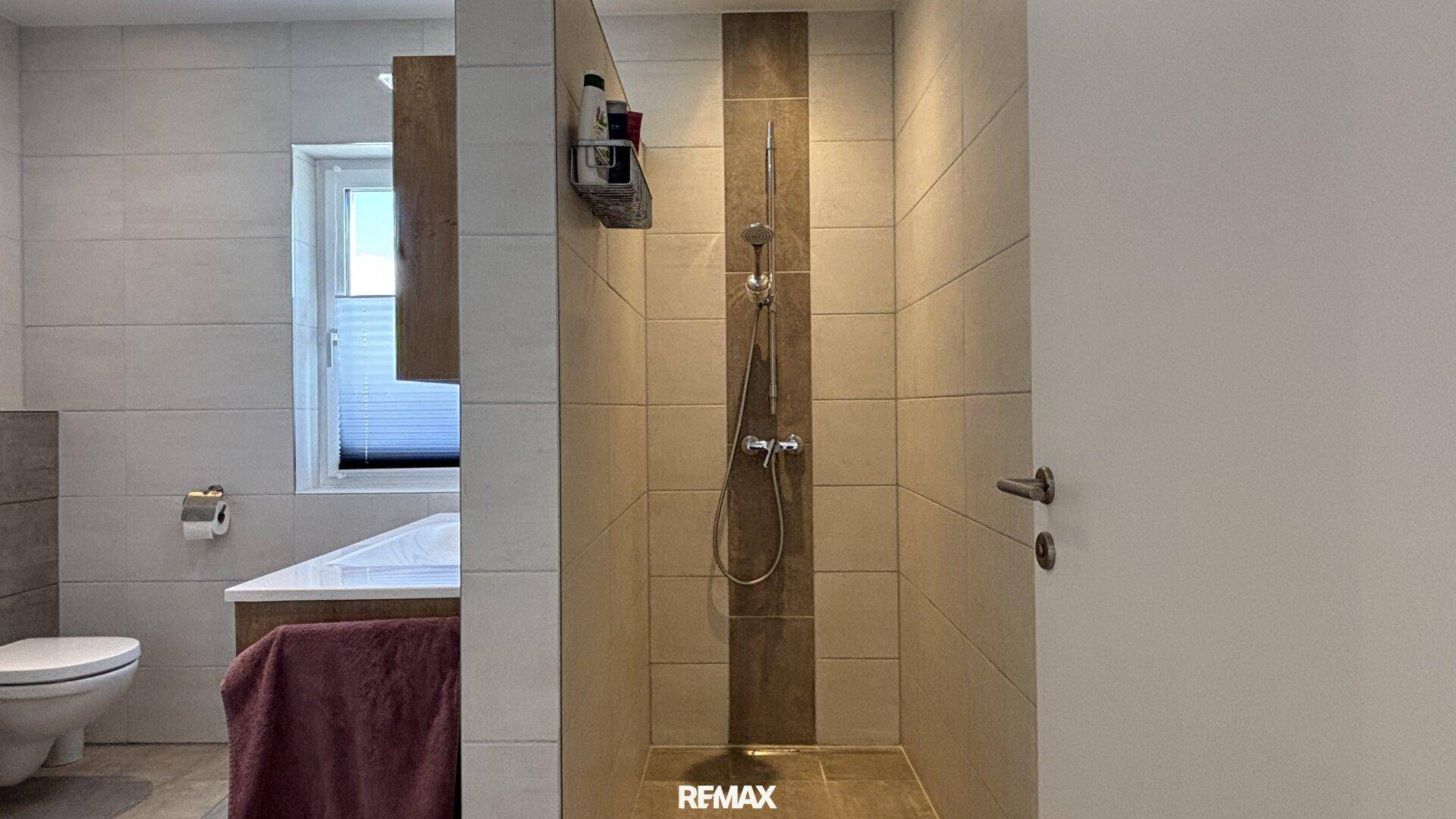 Geräumige, ebenerdige Dusche im modernen Badezimmer, vollständig gefliest für einfache Pflege.