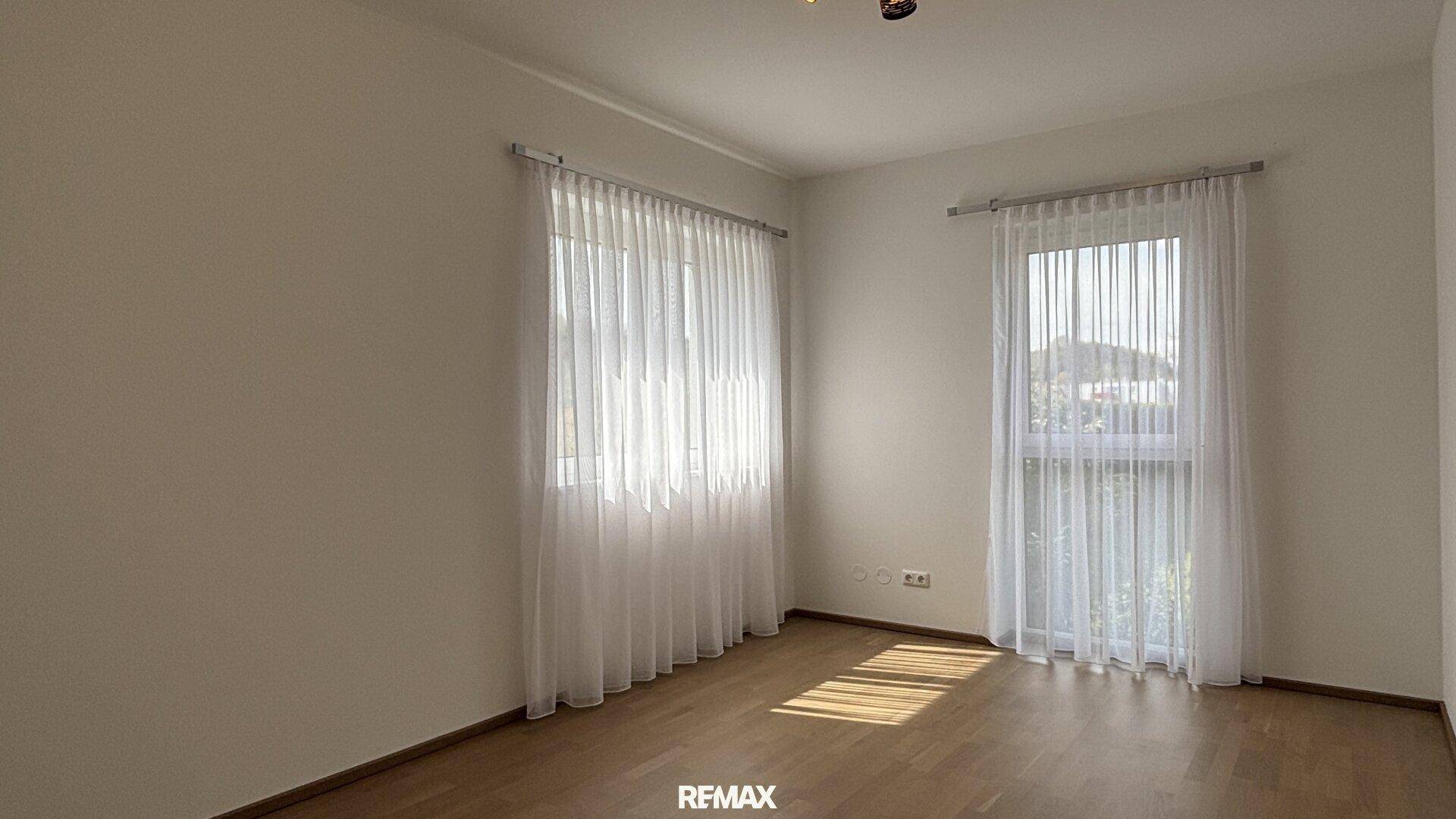 Helles, leeres Zimmer mit zwei Fenstern und schönem Holzfußboden, vielseitig nutzbar.