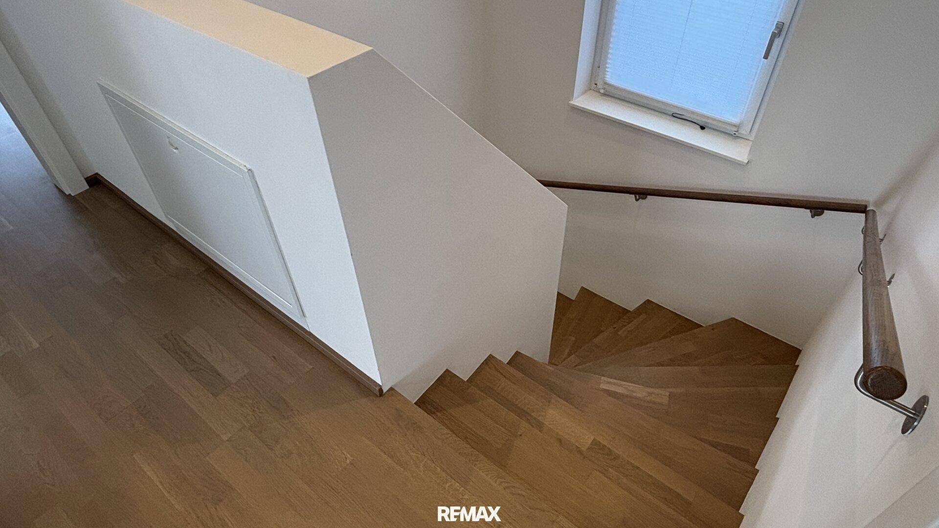 Elegante Holztreppe mit Handlauf, die die Etagen verbindet, mit passendem Holzfußboden.