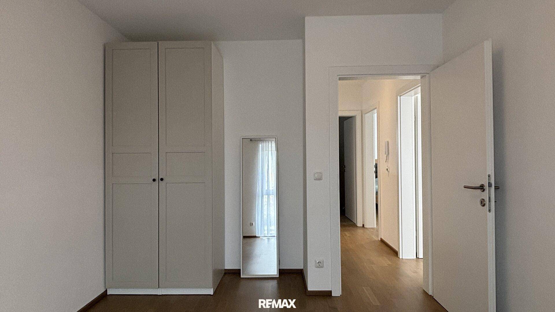 Zimmer mit hellem Kleiderschrank und großem Spiegel, ideal als Schlaf- oder Ankleidezimmer.