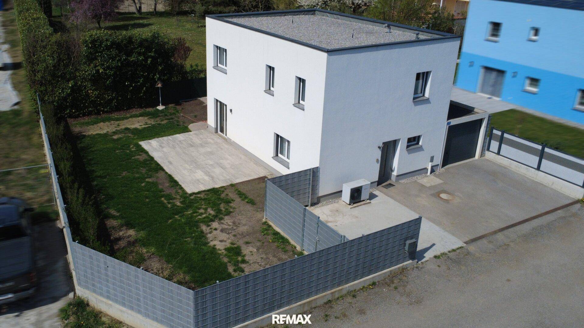 Gesamtansicht des modernen Einfamilienhauses von oben mit Garten, Terrasse und Zufahrt.
