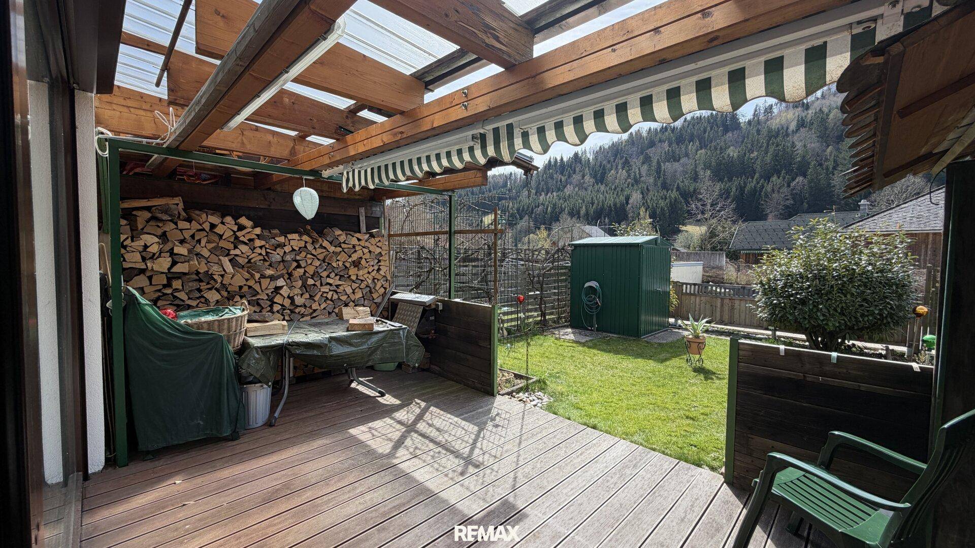 Überdachte Holzterrasse mit Bergblick und Lagerplatz für Brennholz.
