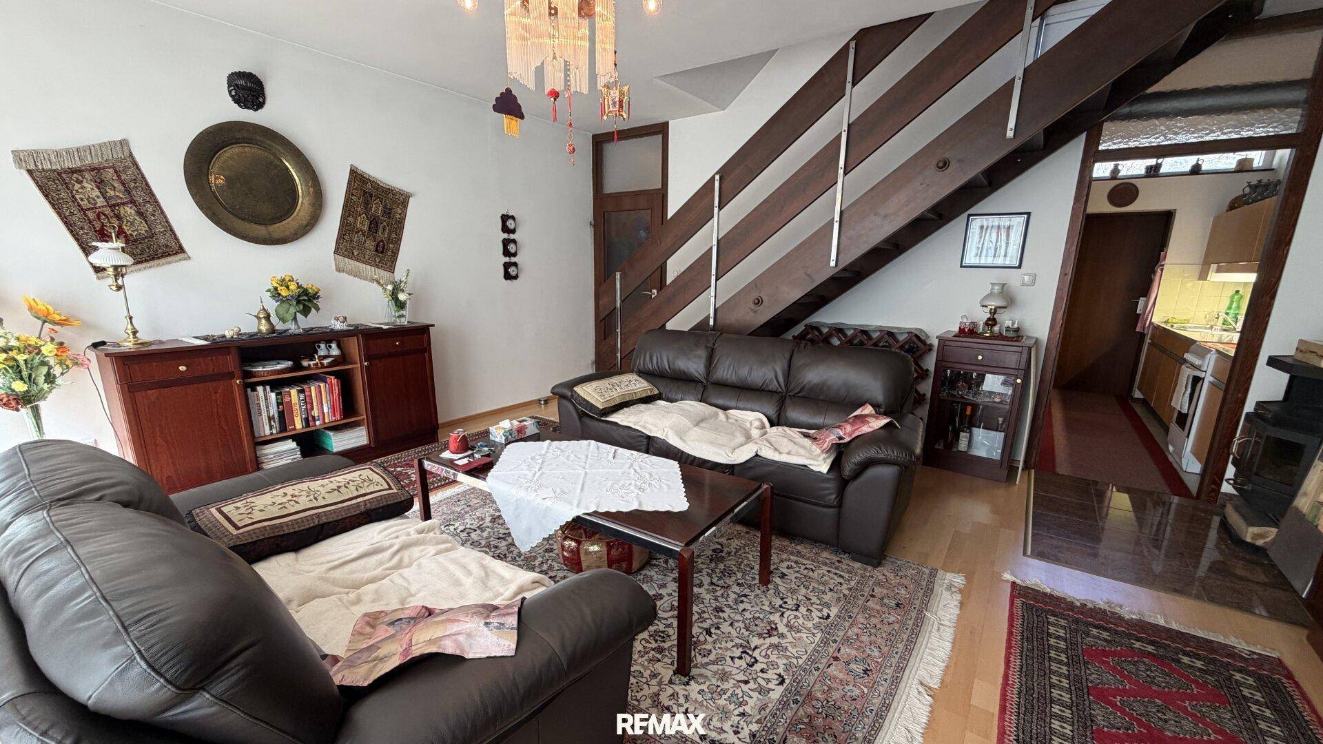 Wohnzimmer mit Ledersofas, Holztreppe und traditionellen Dekorationen.