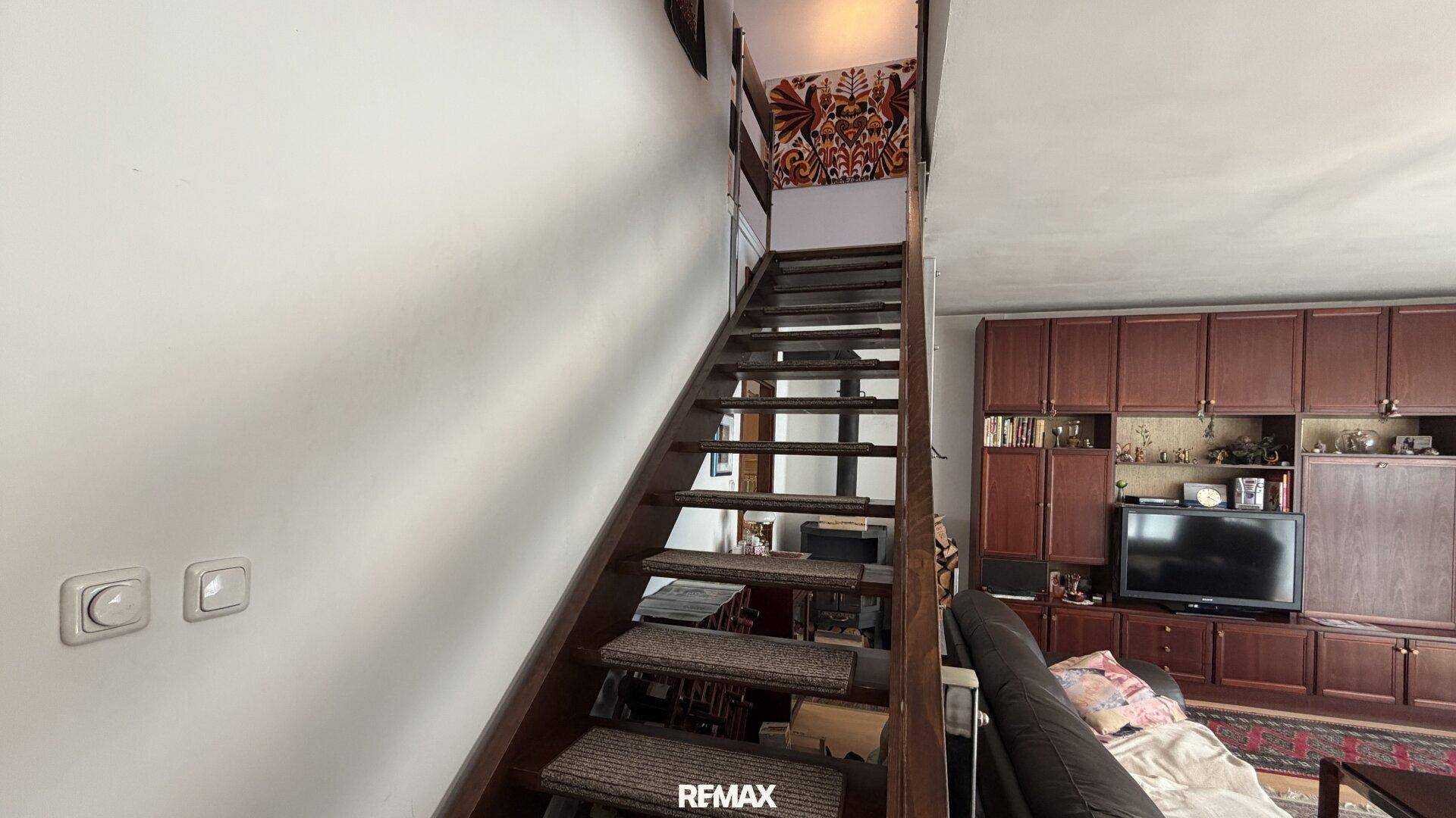 Holztreppe im Wohnzimmer, die in die obere Etage führt, mit Blick auf die Einrichtung.