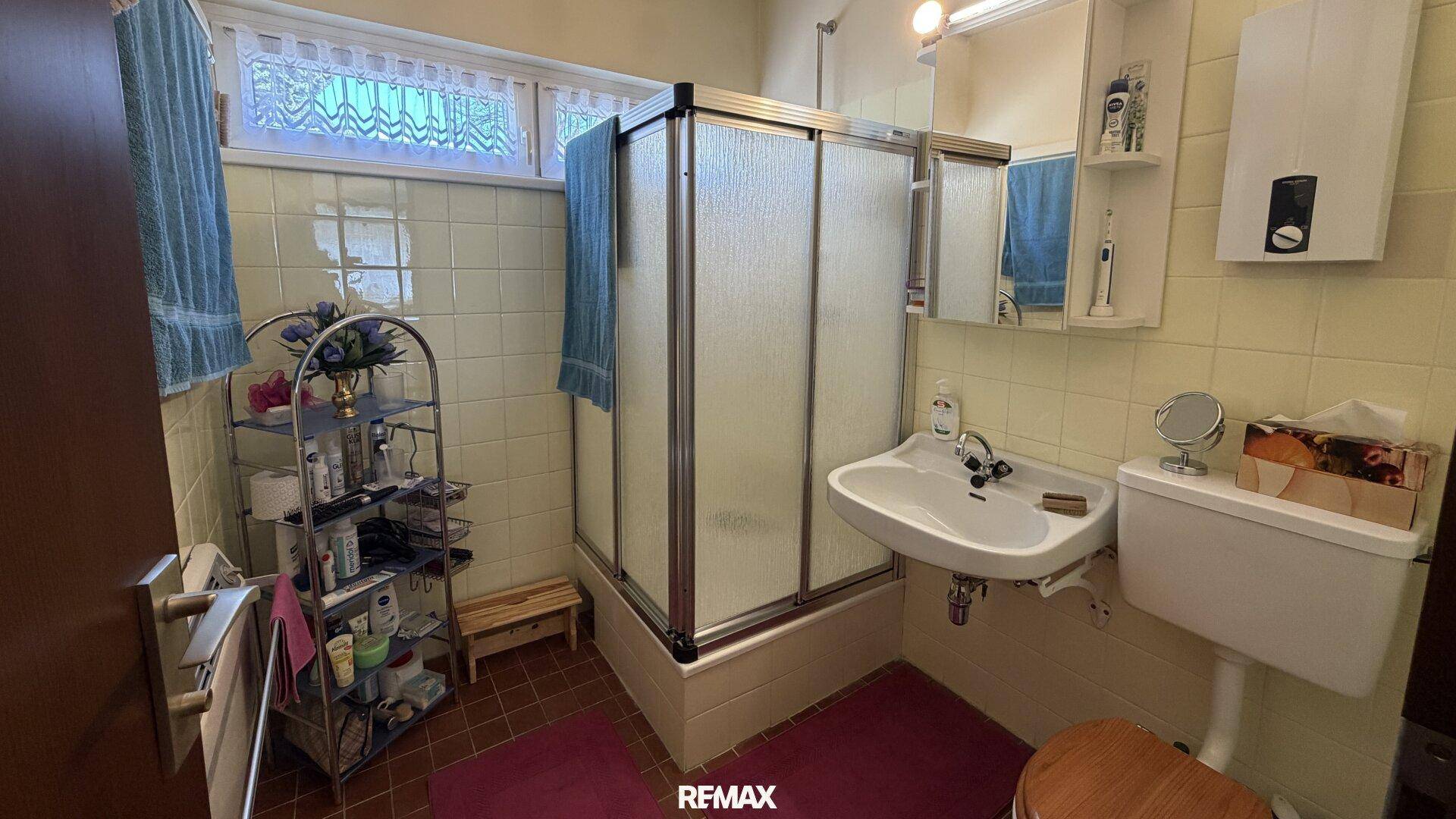Badezimmer mit Duschkabine, Waschbecken und WC, ausgestattet mit gelben Fliesen.