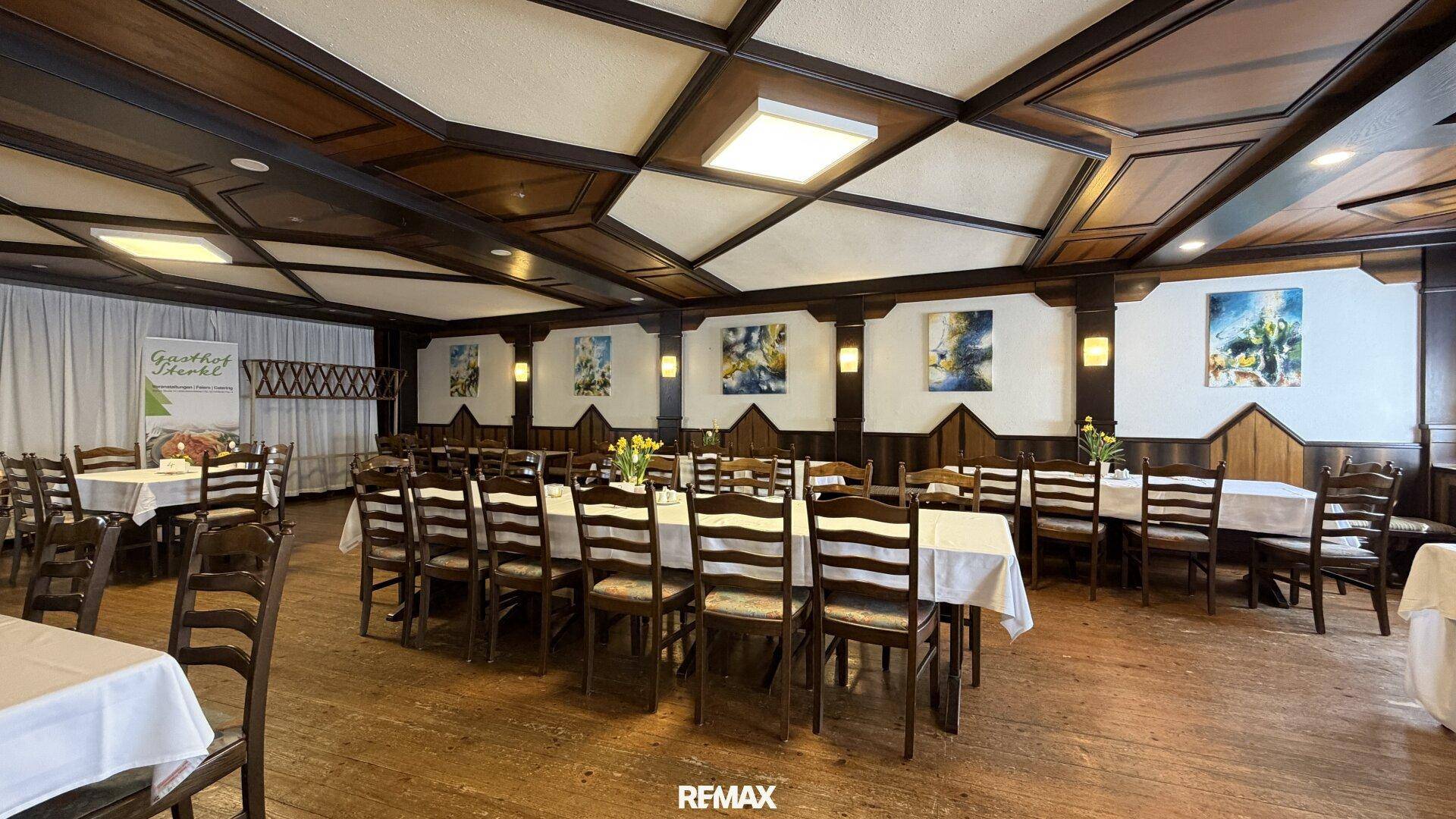 Geräumiger Speisesaal mit Holzbalkendecke, festlich gedeckten Tischen und traditioneller Einrichtung.