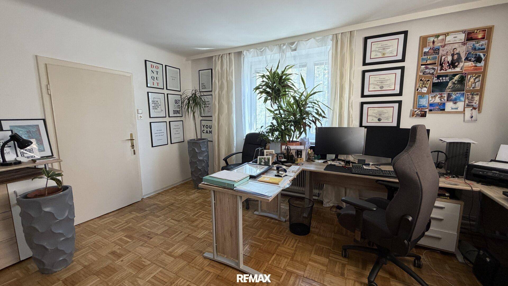Helles Büro mit zwei Schreibtischen, Bürostühlen und Pflanzen, ausgestattet mit Parkettboden.