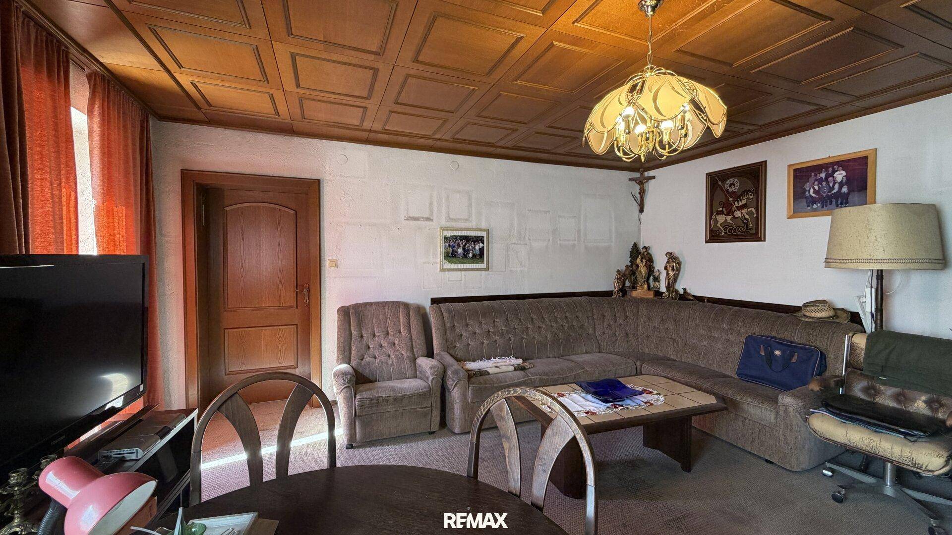 Geräumiges Wohnzimmer mit Kassettendecke aus Holz, großem Sofa und traditioneller Dekoration.
