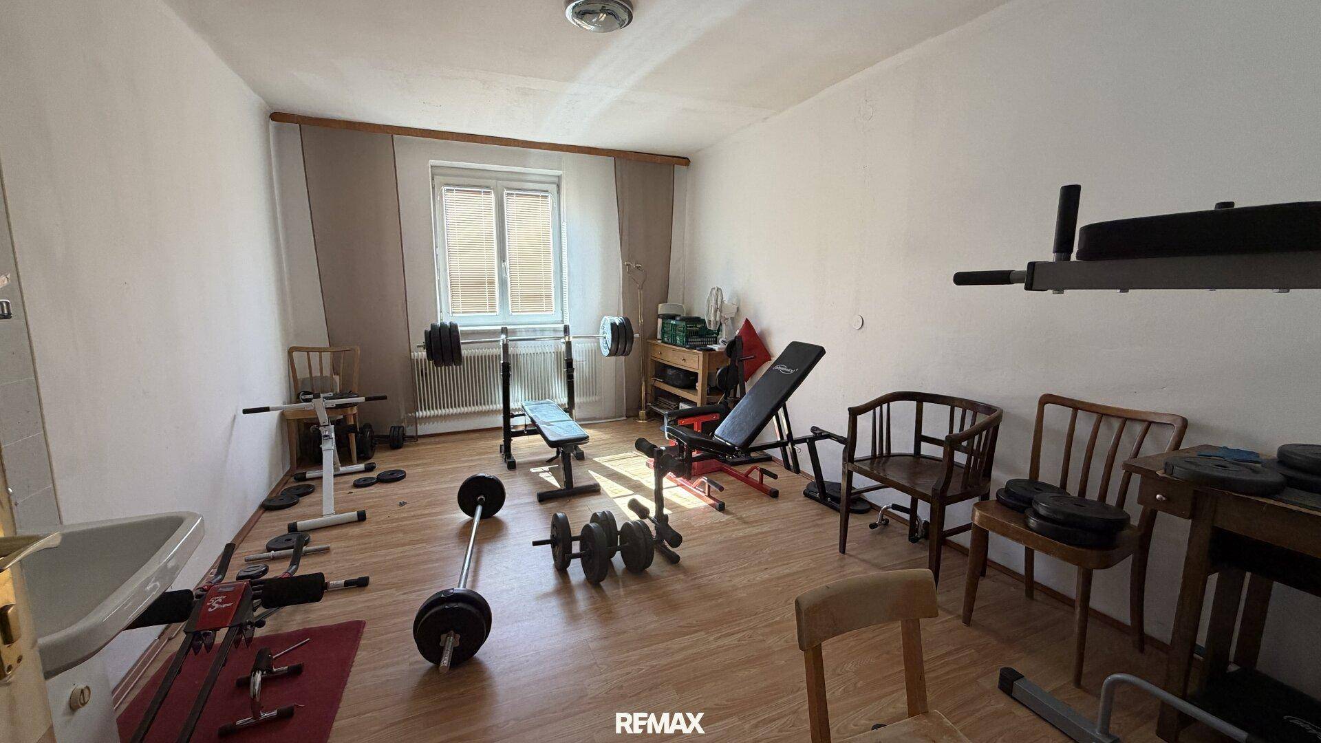 Raum eingerichtet als Fitnessstudio mit Gewichten und Trainingsbänken, ideal für das Heimtraining.