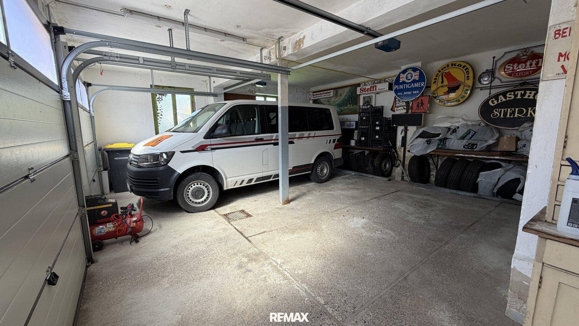 Geräumige Garage mit geparktem Lieferwagen, Werkzeugen und alten Werbeschildern an der Wand.