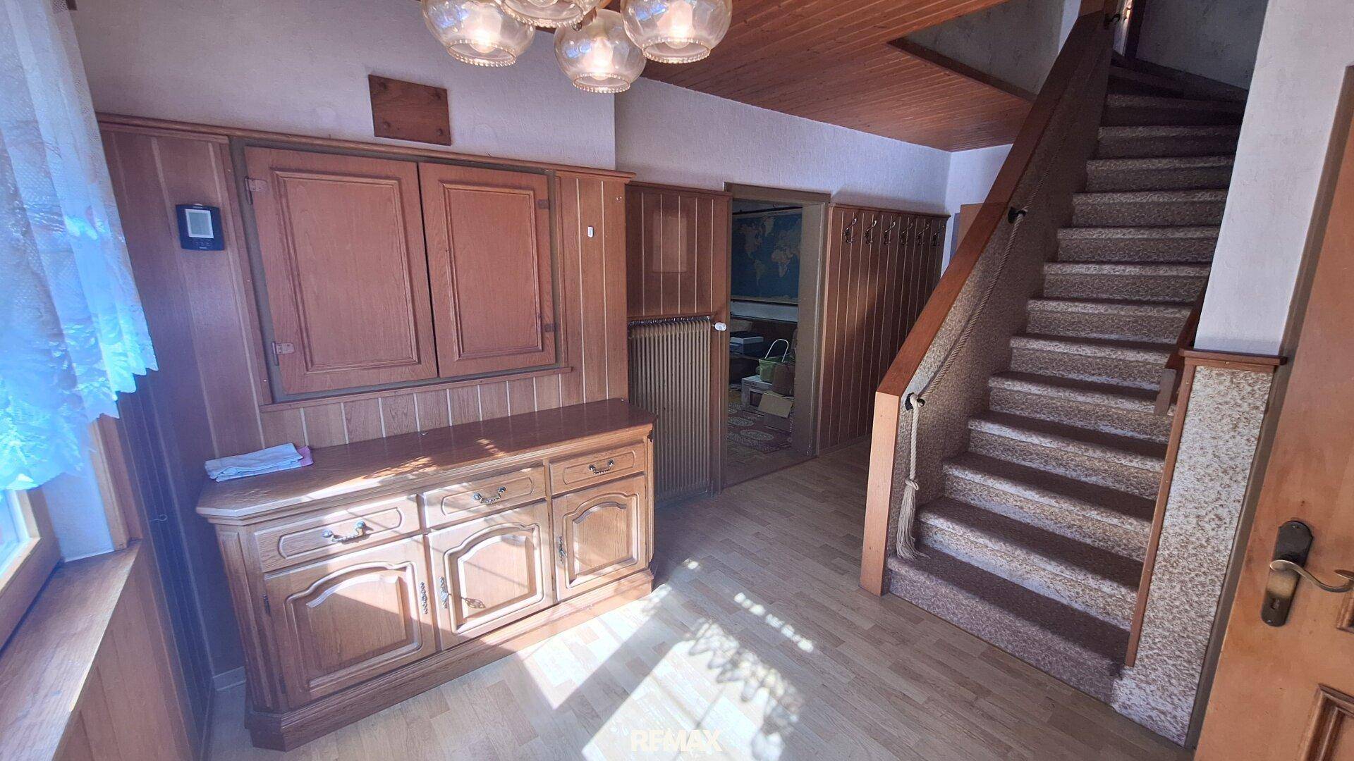 Eingangsbereich mit Holzmöbeln, Teppichtreppe und rustikaler Holzdecke.