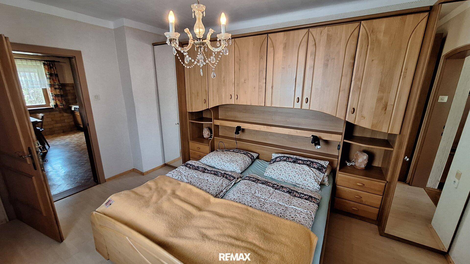 Schlafzimmer mit großem Einbauschrank, Doppelbett und Kronleuchter.