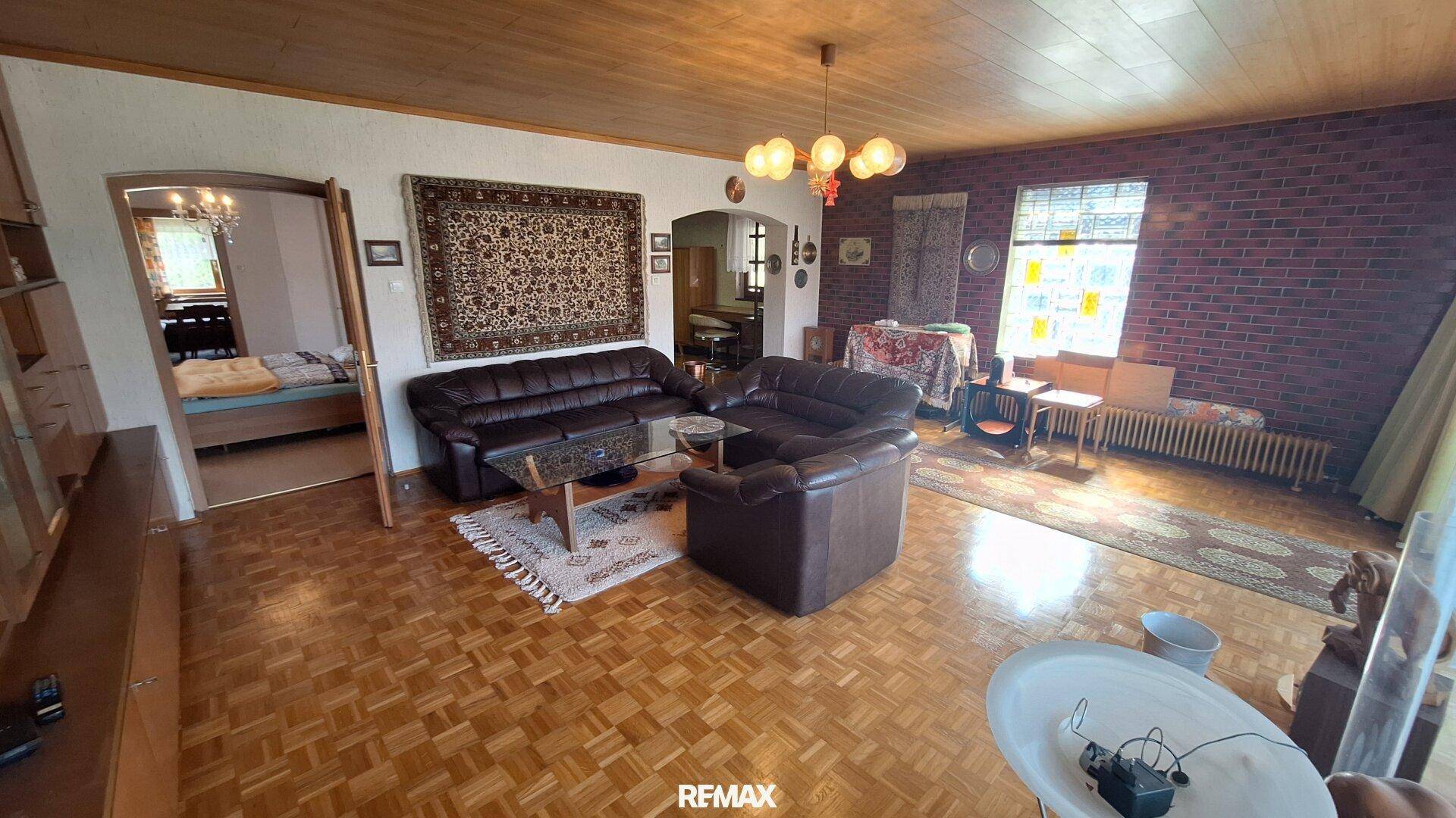 Gemütliches Wohnzimmer mit Parkettboden, Ledersofas und rustikaler Holzdecke.