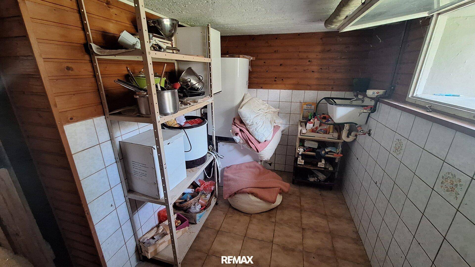 Abstellraum im Keller mit Regalen, Waschbecken und Holzverkleidung.