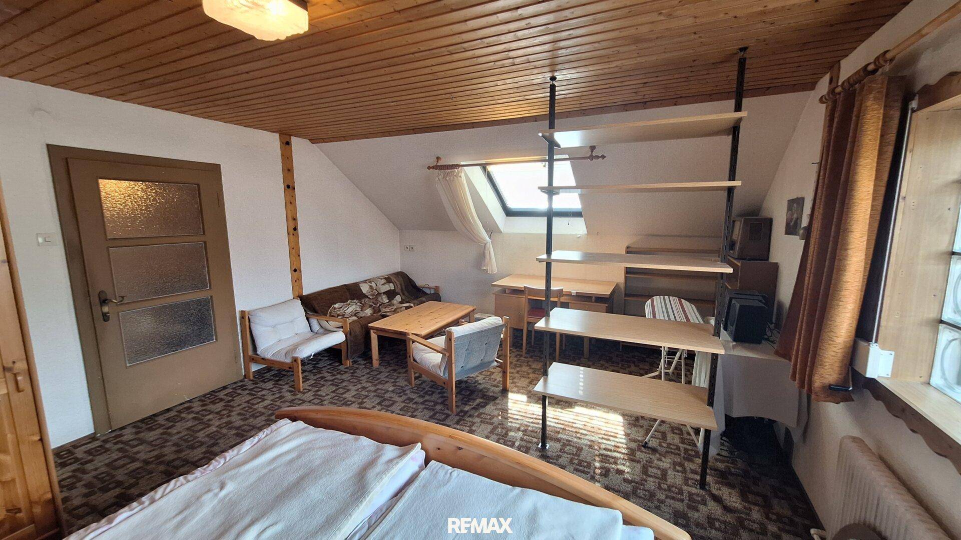 Dachgeschoss-Schlafzimmer mit Holzbett, Teppichboden und Dachfenster für natürliches Licht.