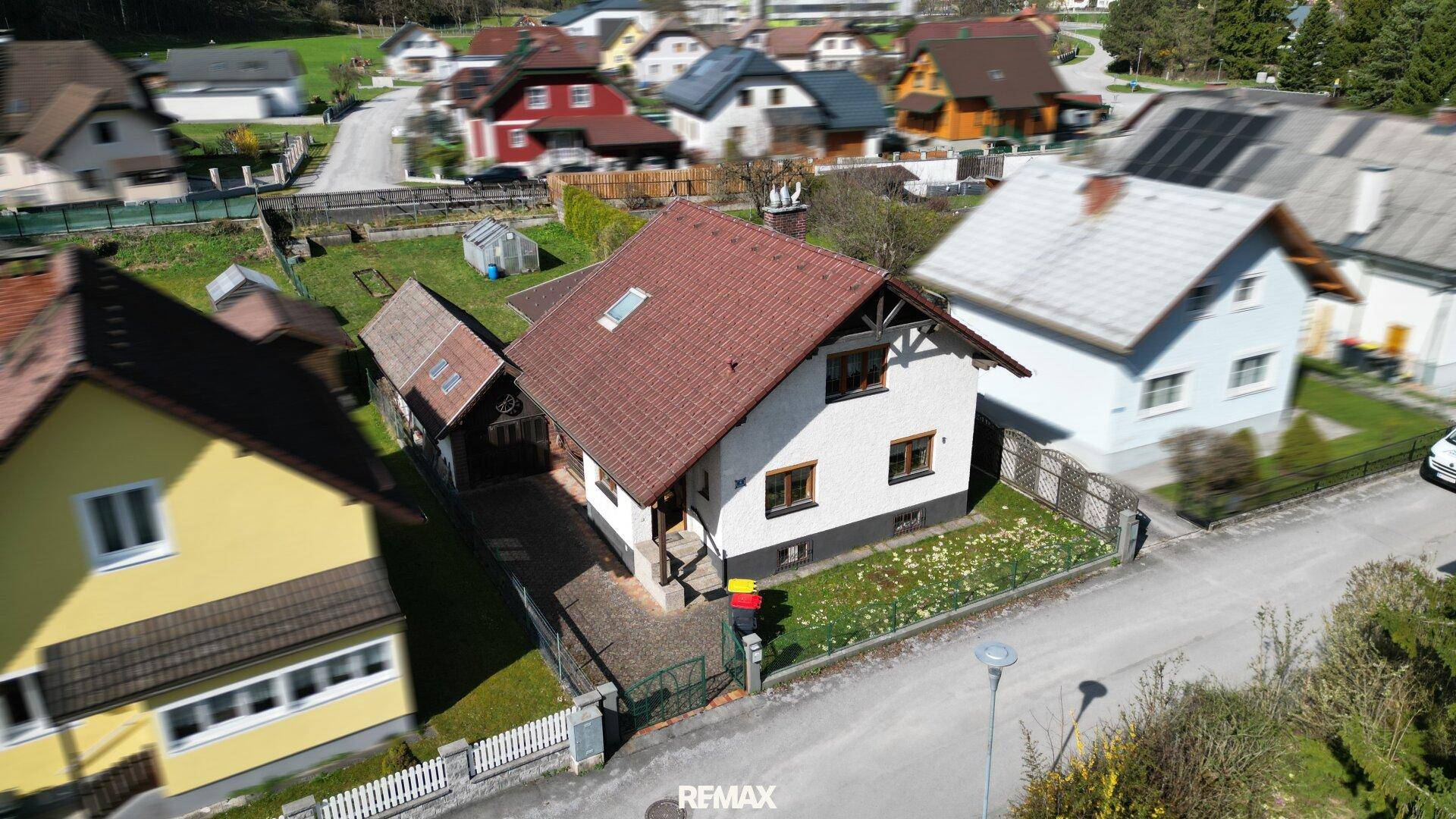 Luftaufnahme eines Einfamilienhauses mit rotem Dach in einer ländlichen Wohnsiedlung.