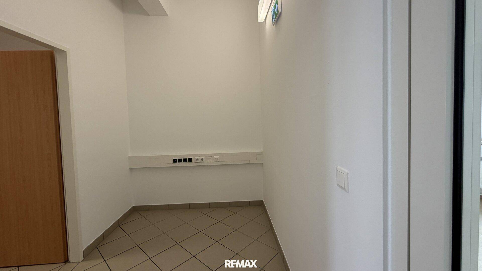 Kleiner Flurbereich mit Fliesenboden und einer Holztür, funktional und sauber gehalten.