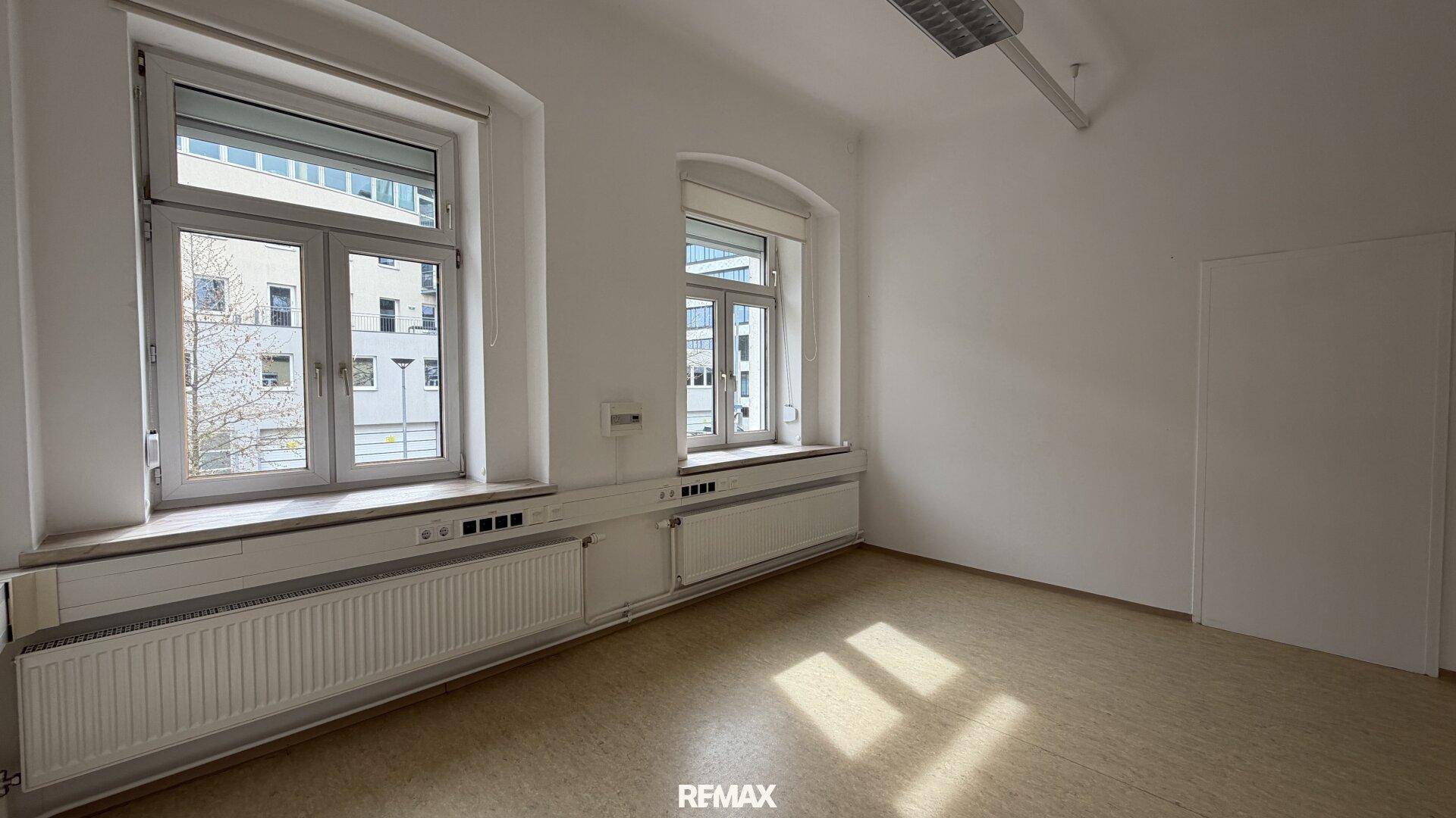 Heller Büroraum mit zwei Fenstern, die einen Blick nach draußen ermöglichen und viel Licht spenden.