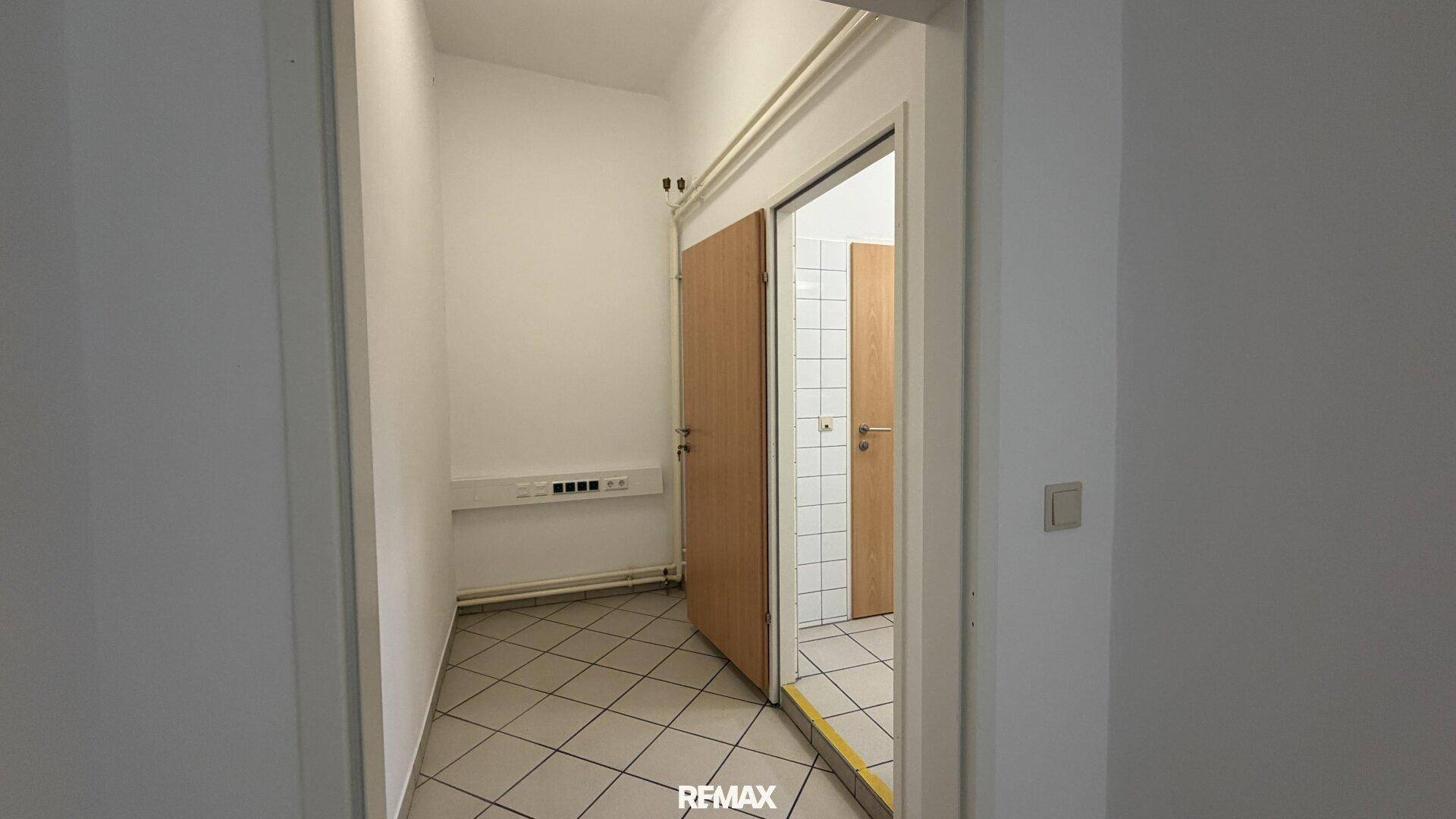 Kleiner Vorraum mit gefliestem Boden und Türen, die zu den Sanitäranlagen führen.