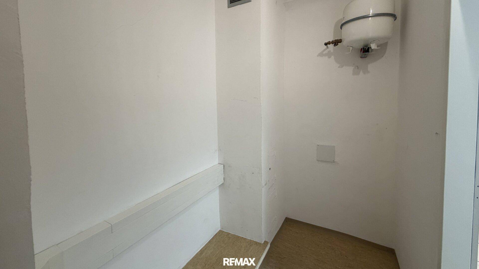 Kleiner Abstellraum mit Boiler an der Wand und Linoleumboden.