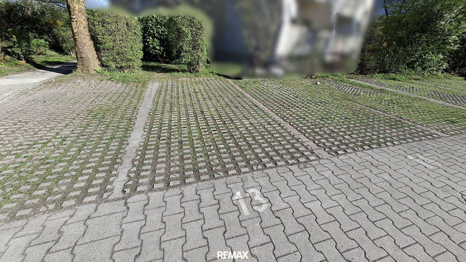 Außenparkplätze mit Rasengittersteinen und markierten Stellplätzen für Fahrzeuge.