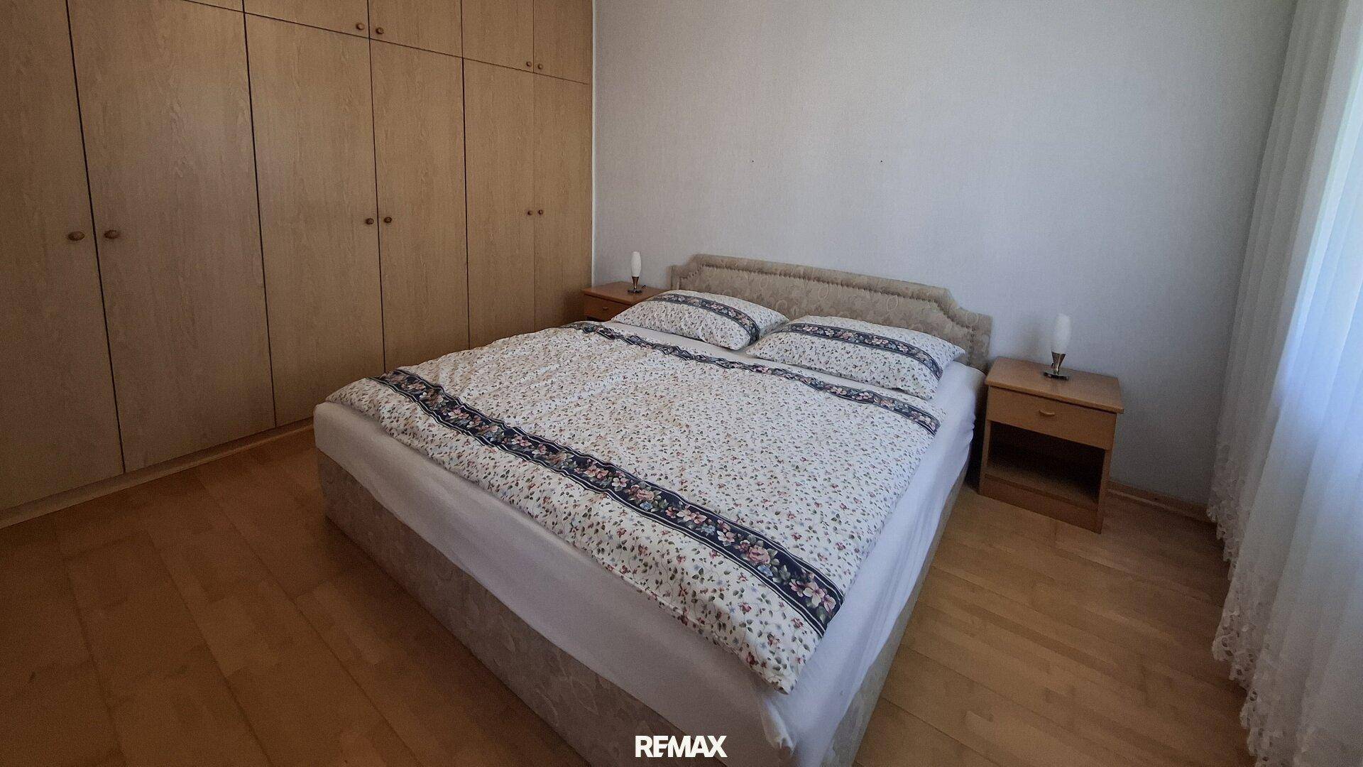 Schlafzimmer mit Doppelbett und geräumigen Einbauschränken aus Holz, bietet viel Stauraum.