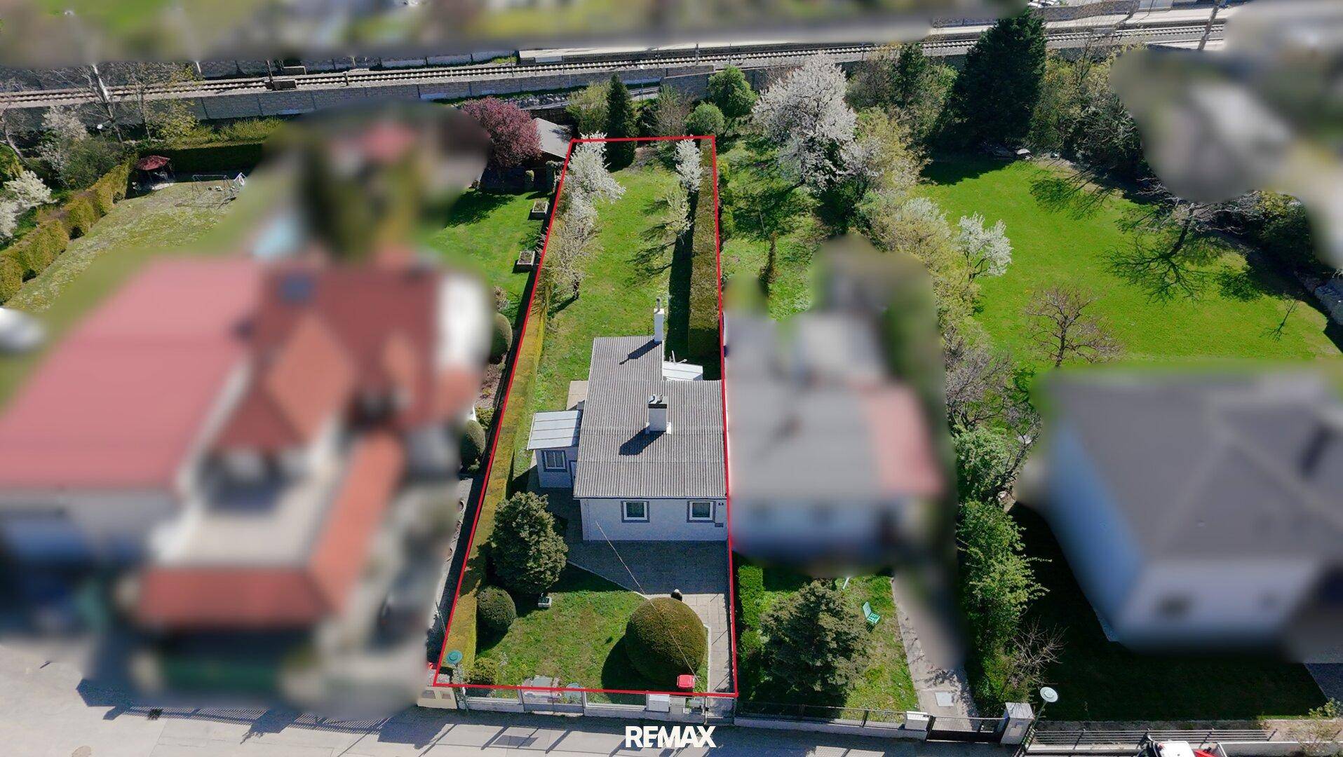 Weitläufige Luftaufnahme des Grundstücks mit roter Umrandung und angrenzenden Bahngleisen.
