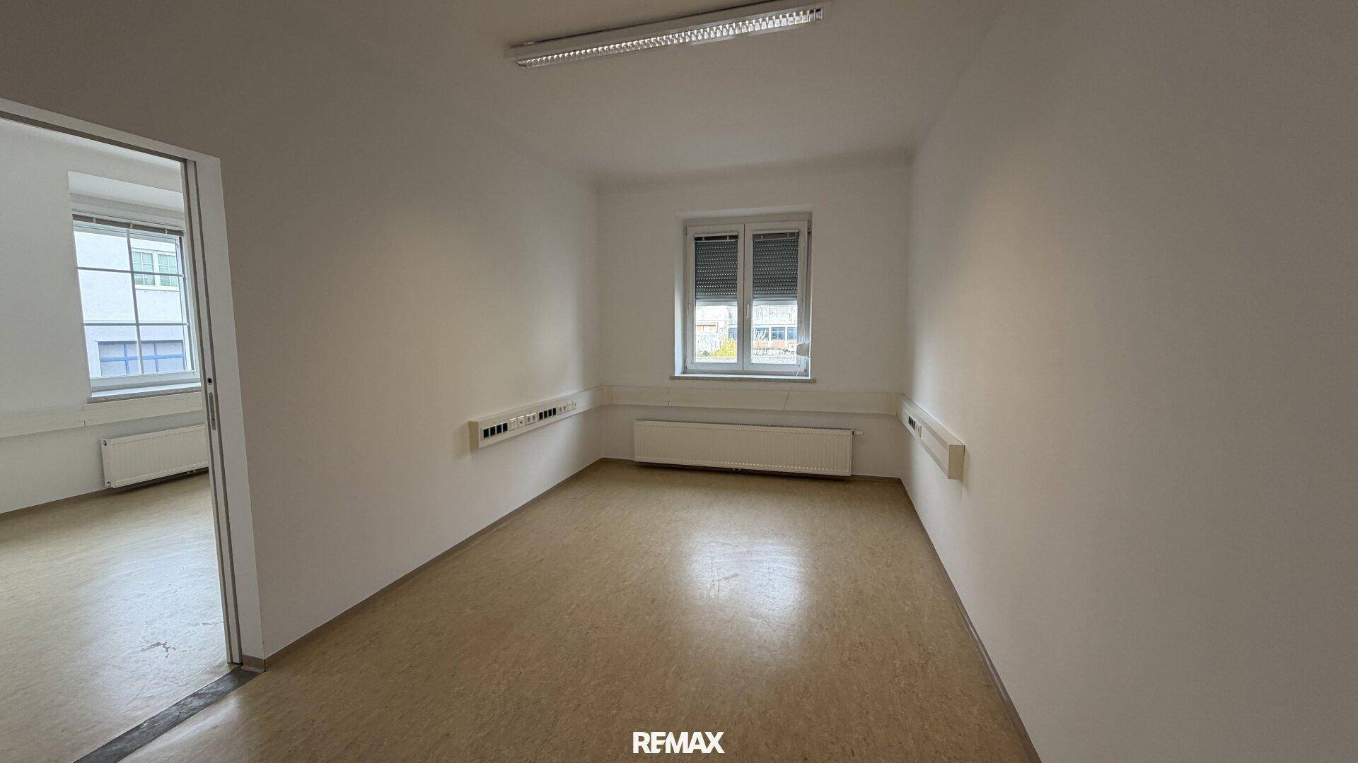 Büroraum mit Linoleumboden und einem Fenster mit Jalousien, funktional und hell.