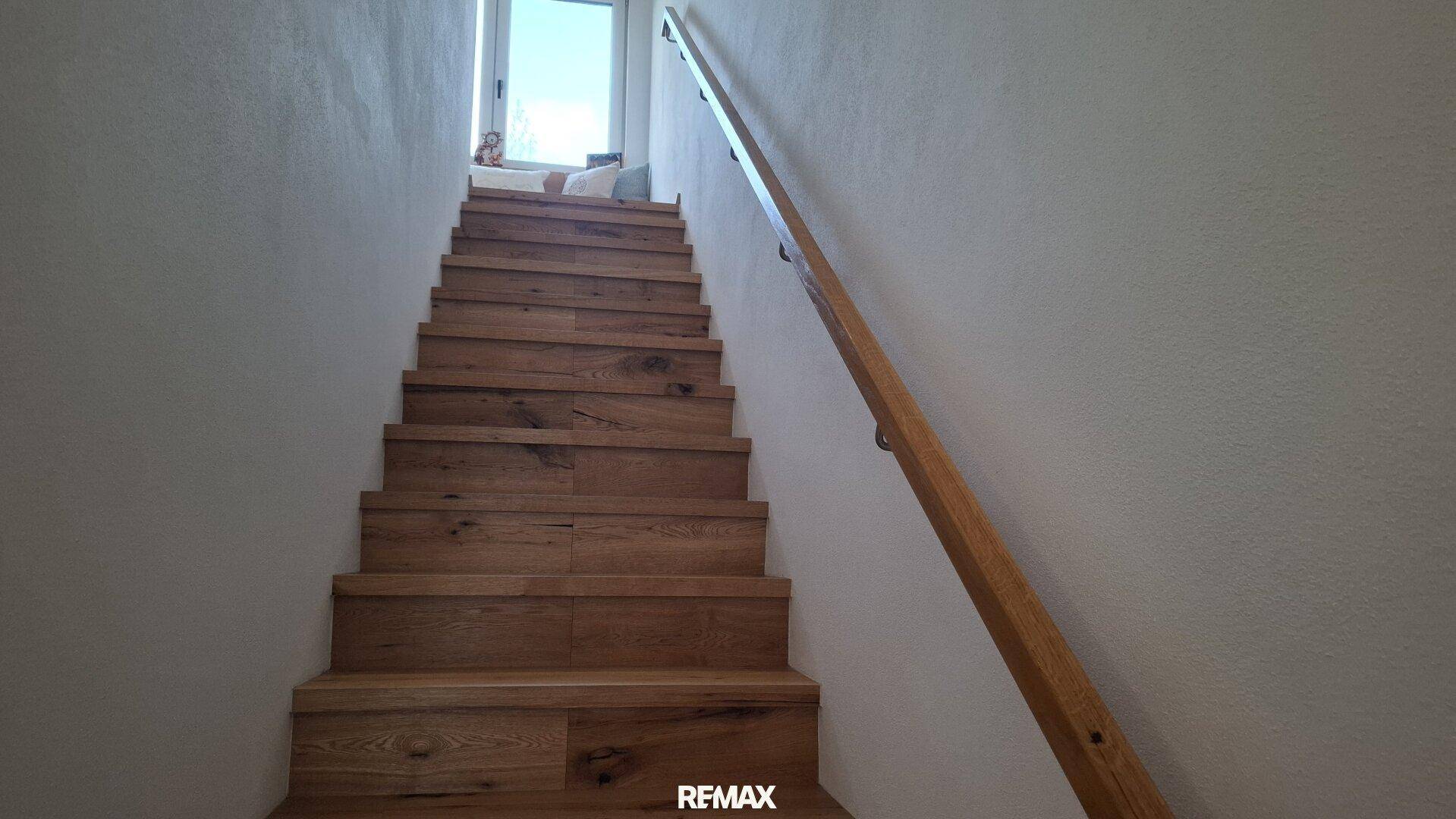 Holztreppe mit schlichtem Holzgeländer, die in die oberen Stockwerke führt.