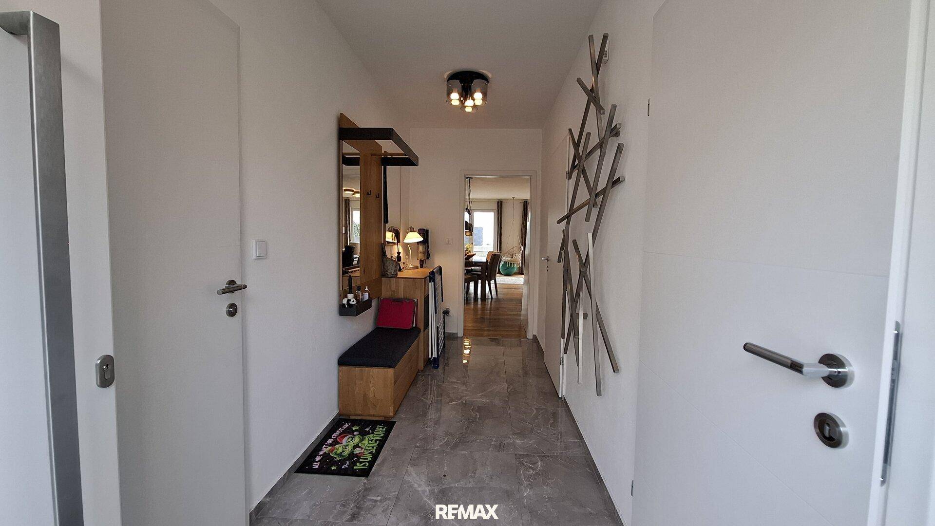 Heller Flur mit grauen Fliesen, einer Garderobe und modernen weißen Türen.