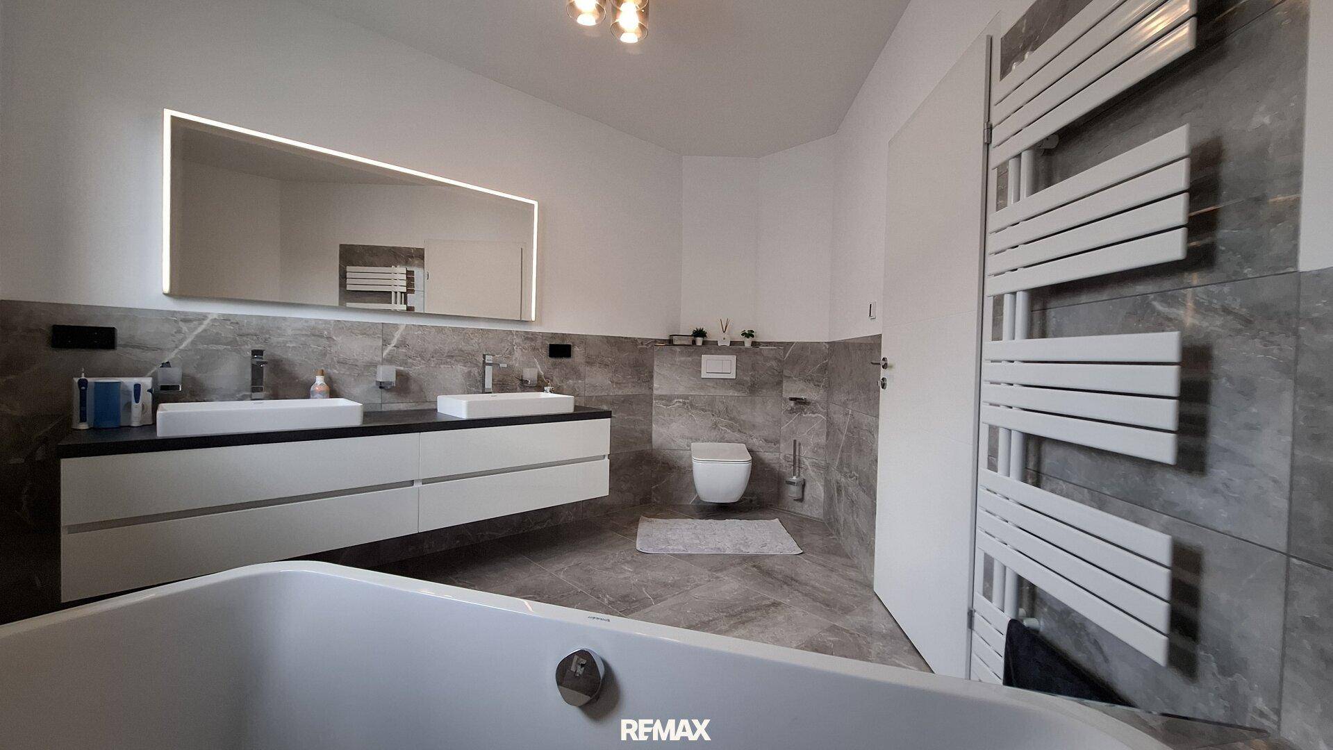 Großes modernes Badezimmer mit Doppelwaschbecken, Badewanne und beheiztem Handtuchhalter.