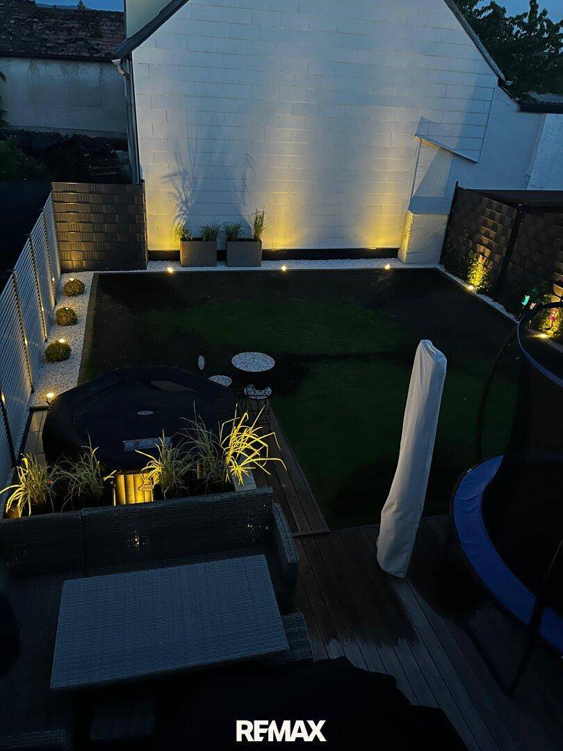 Beleuchteter Garten und Terrasse bei Nacht mit stimmungsvoller Außenbeleuchtung.
