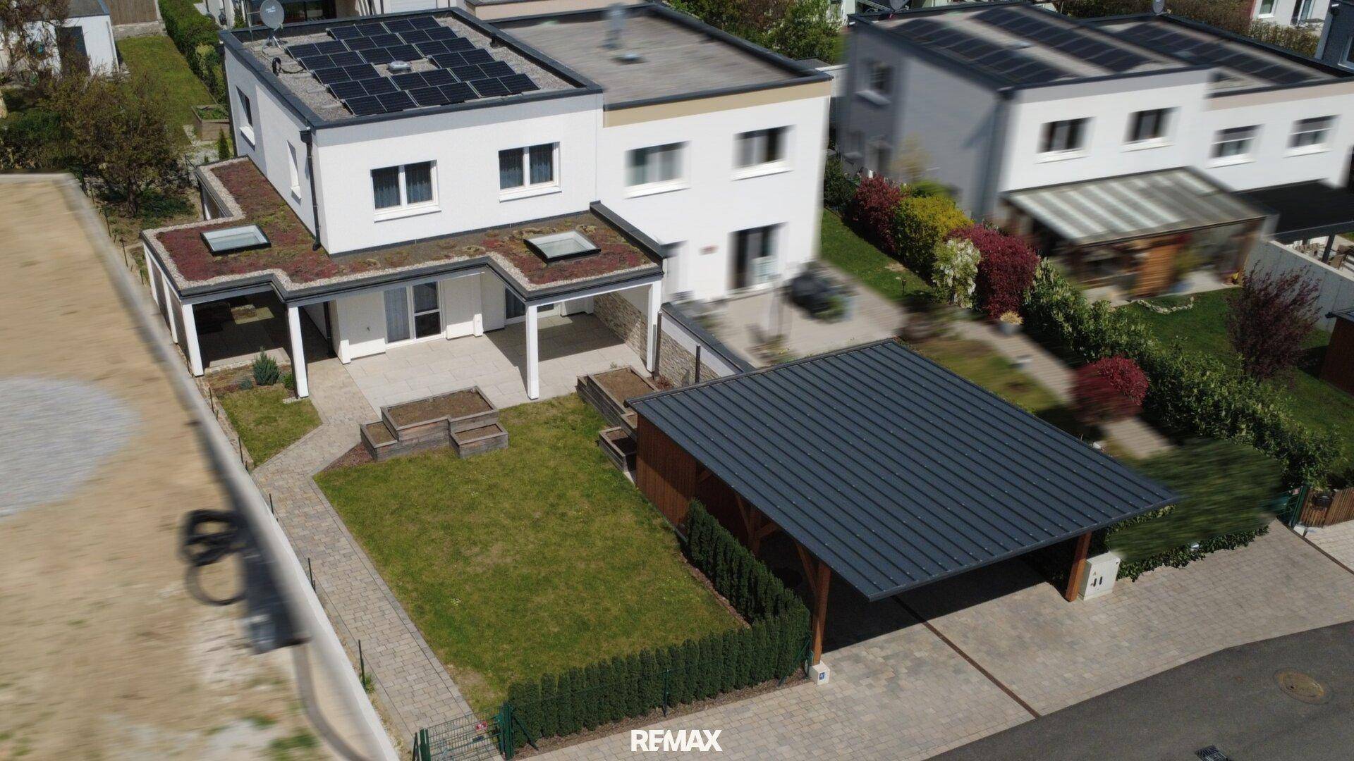 Luftaufnahme des Hauses mit Solaranlage auf dem Dach, Gründach und überdachtem Carport.
