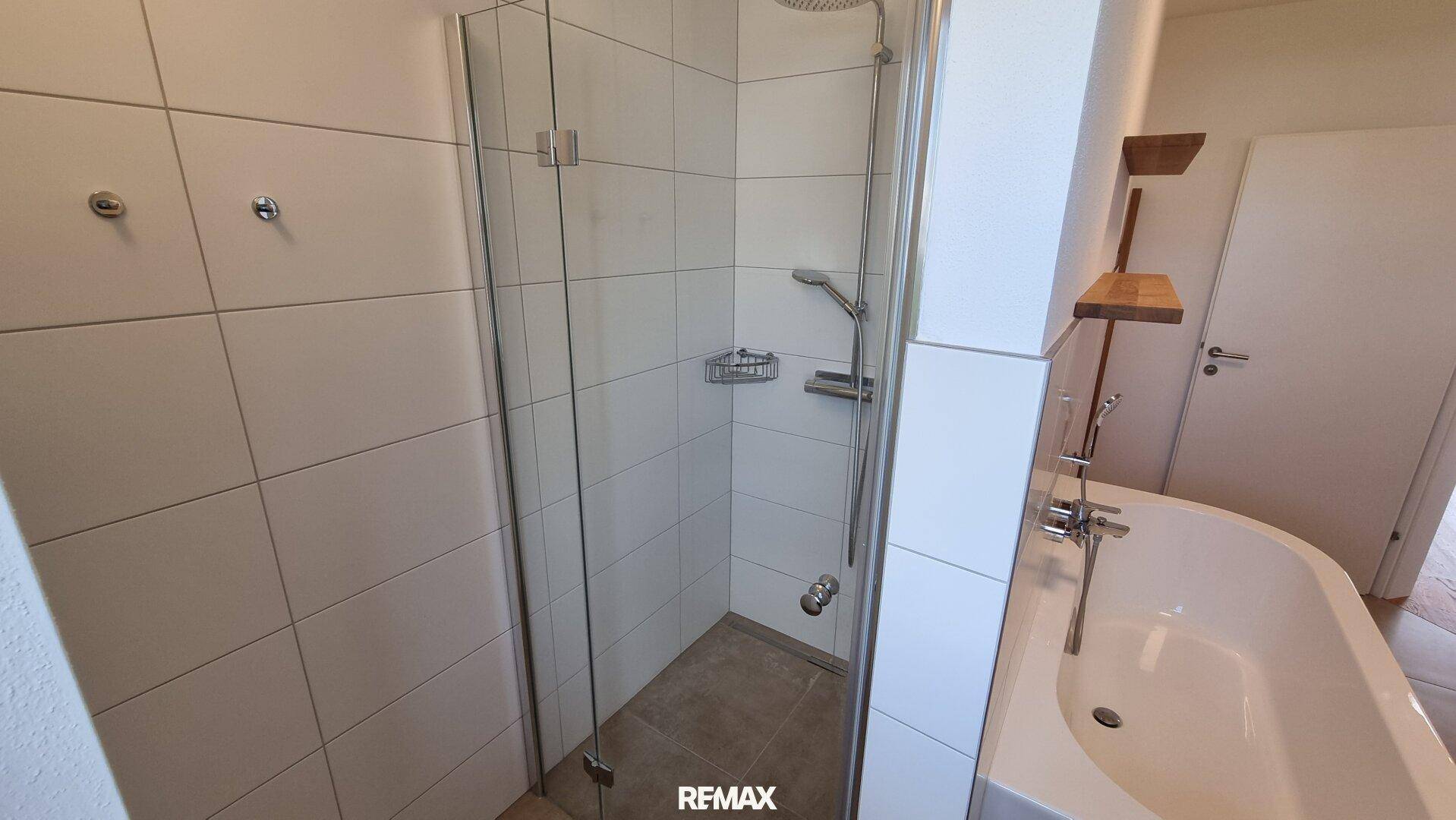 Modernes Badezimmer mit begehbarer Dusche und Badewanne, ausgestattet mit weißen Fliesen.