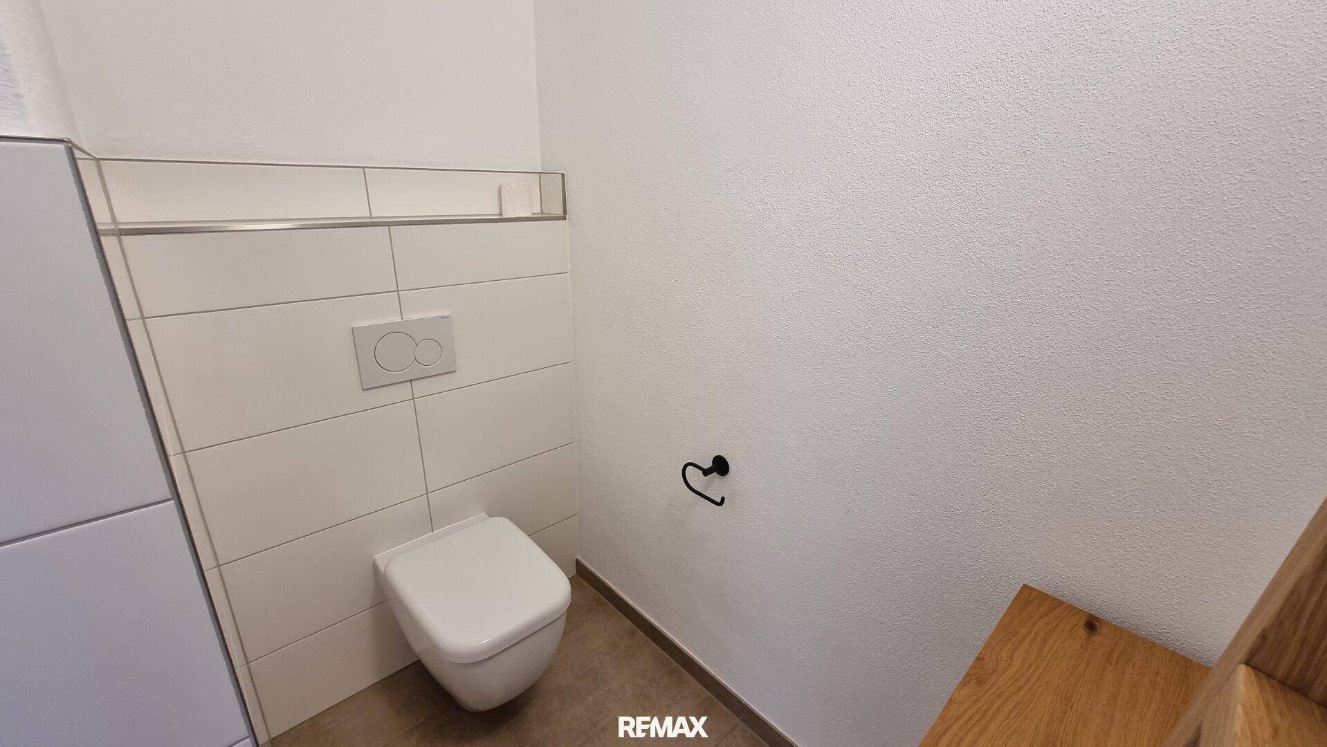 Wandhängende Toilette in einem modernen Badezimmer mit weißen Fliesen.