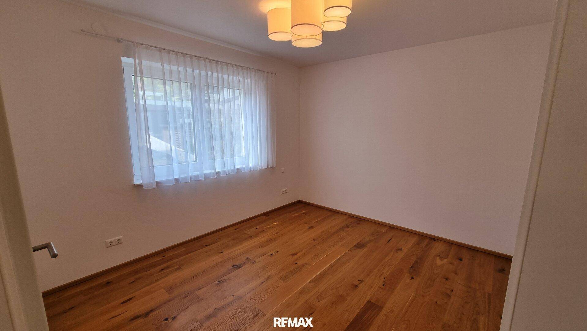 Geräumiges Schlafzimmer mit Holzboden und Fenster, ideal für Ruhe und Entspannung.