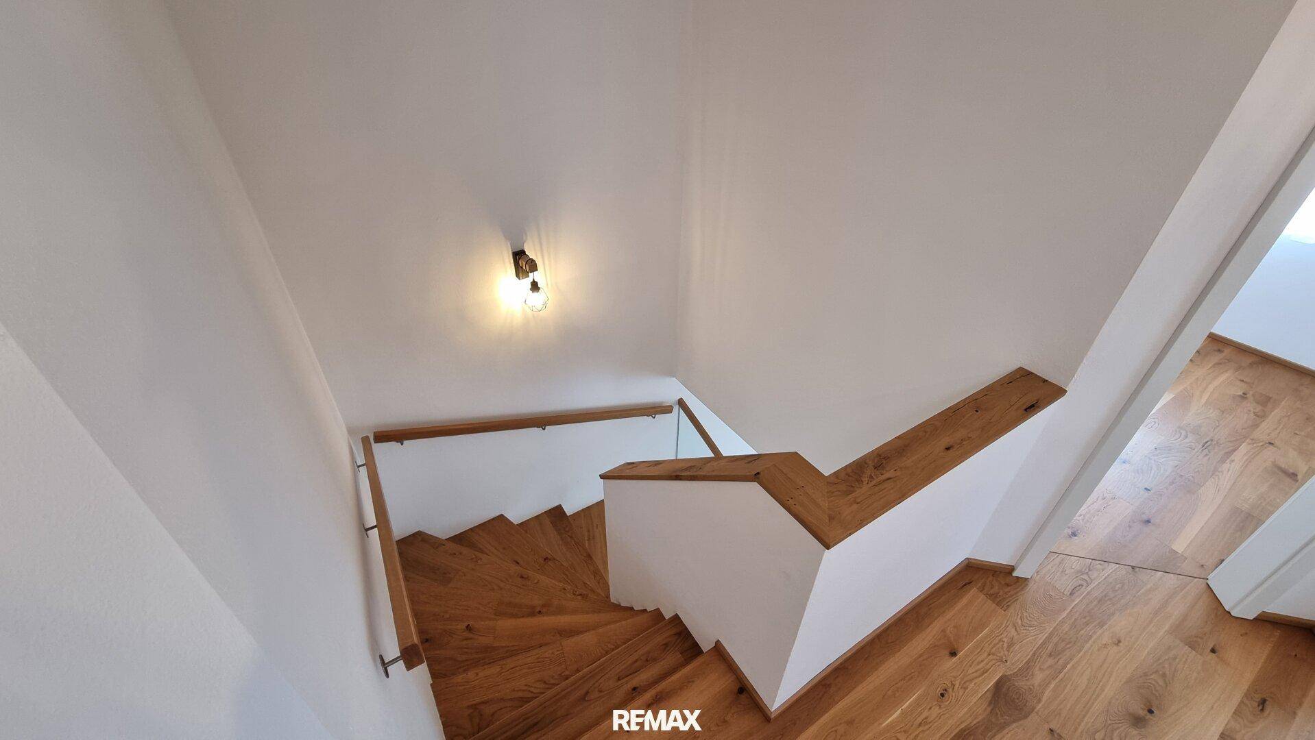 Elegante Holztreppe mit modernem Geländer, die die verschiedenen Etagen des Hauses verbindet.