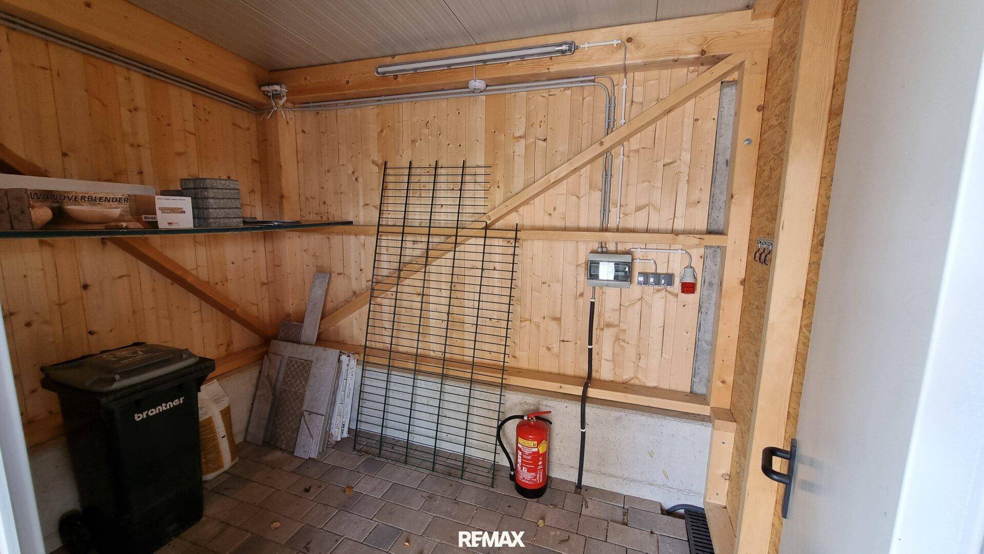 Innenansicht eines Abstellraums mit Holzverkleidung und gepflastertem Boden, bietet praktischen Stauraum.