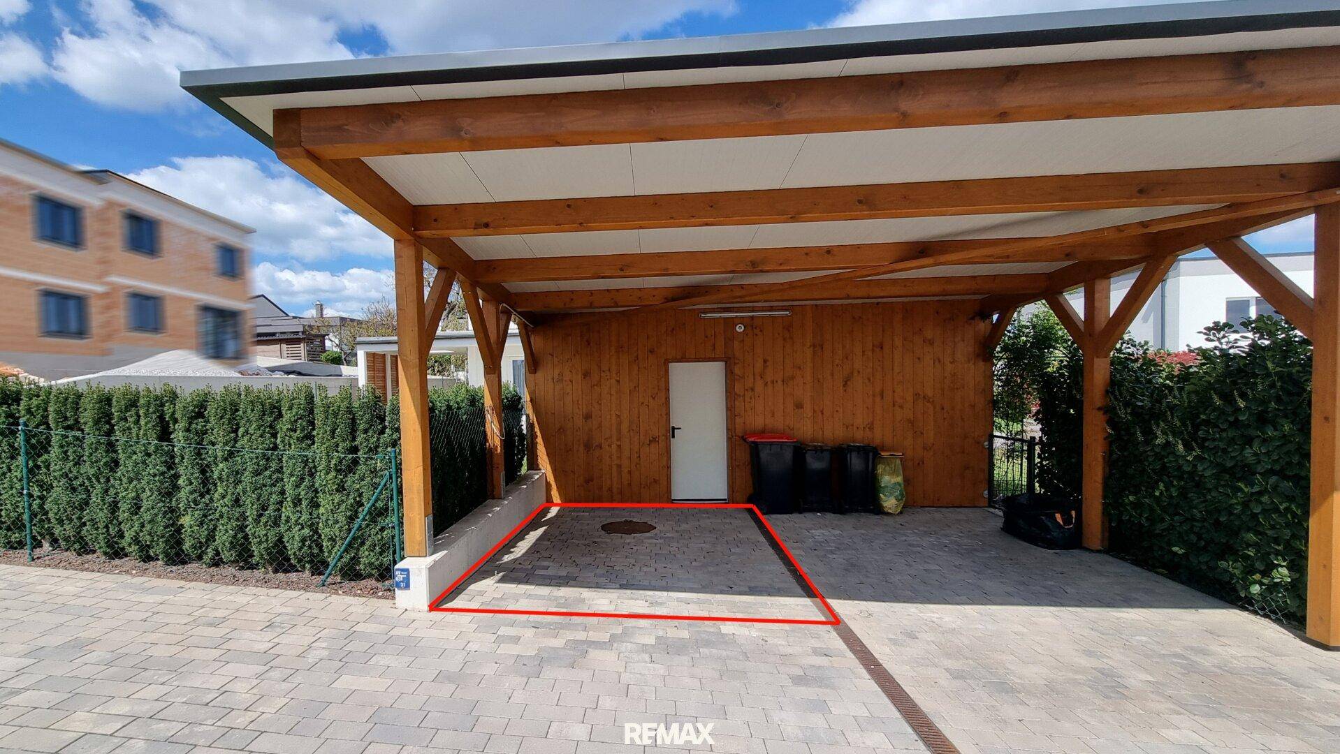 Überdachter Carport mit Holzkonstruktion und gepflastertem Boden, ideal für zwei Fahrzeuge.
