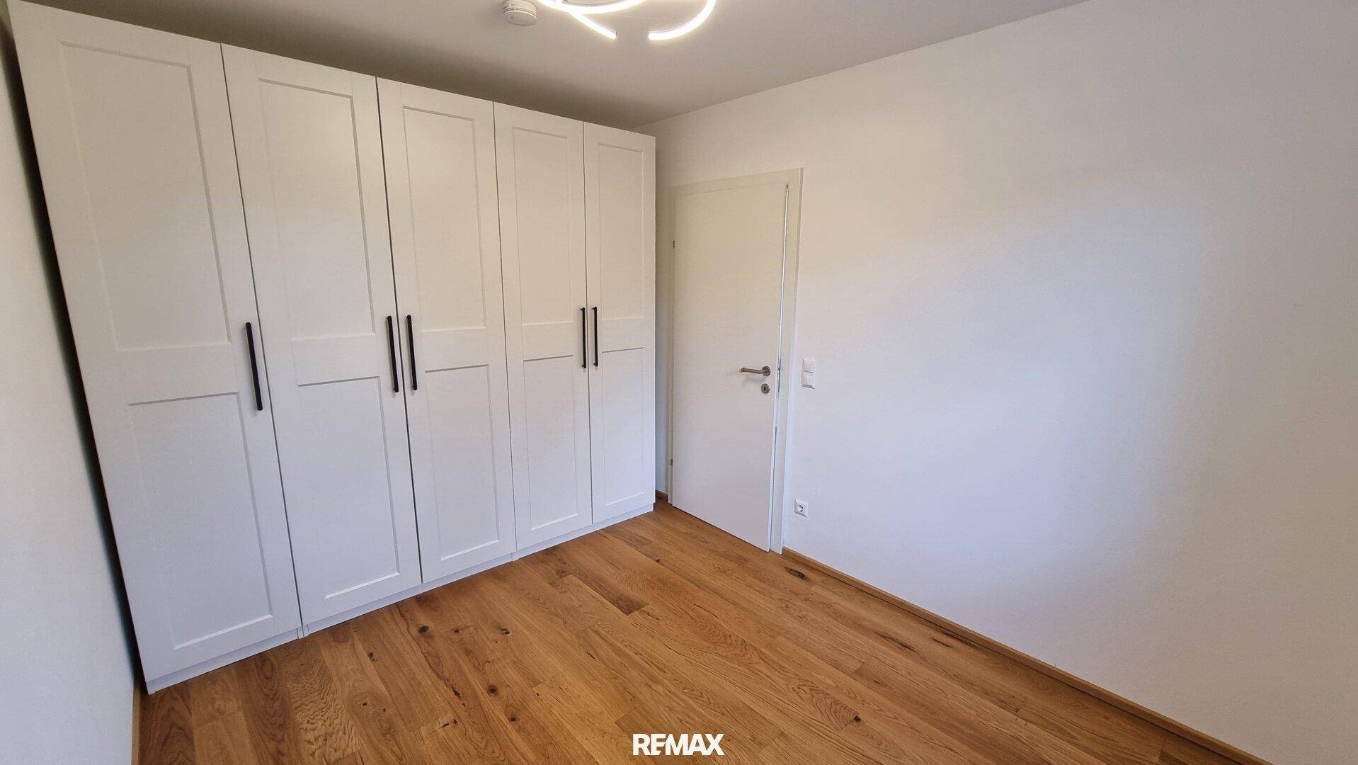 Schlafzimmer mit weißen Einbauschränken und warmem Holzboden, bietet viel Stauraum.