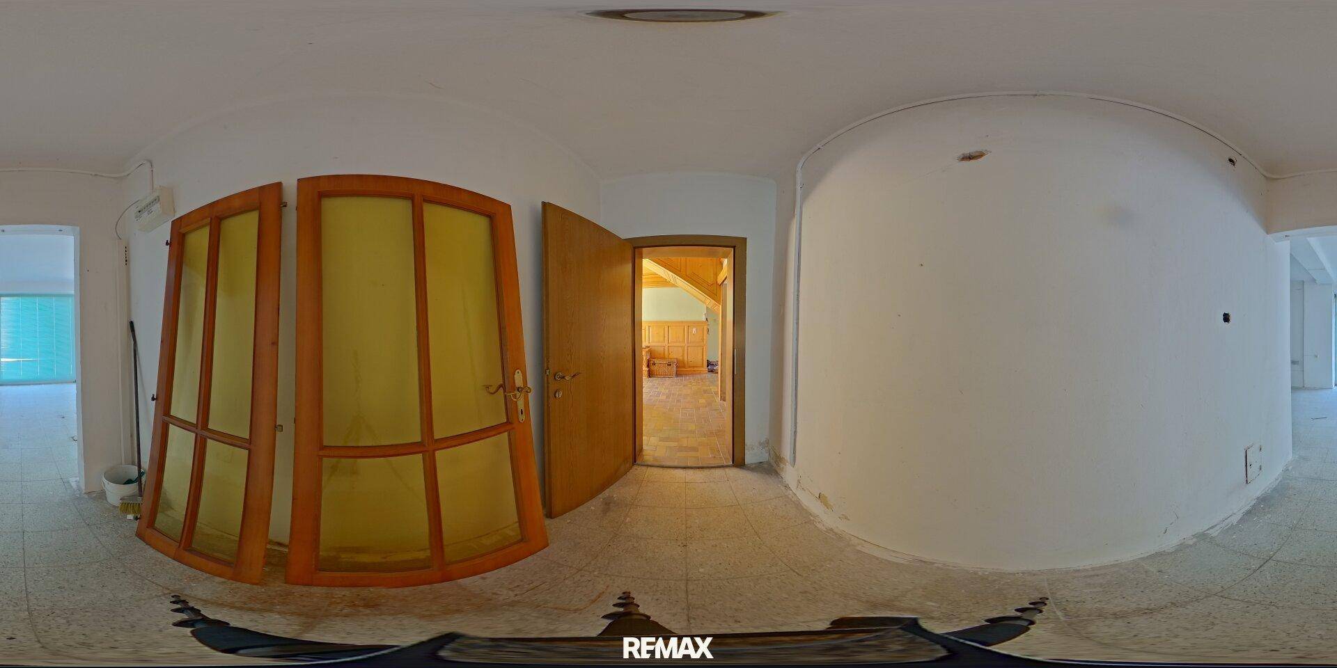 Panoramablick auf einen Flur mit Holztüren und Fliesenboden, der zu weiteren Räumen führt.