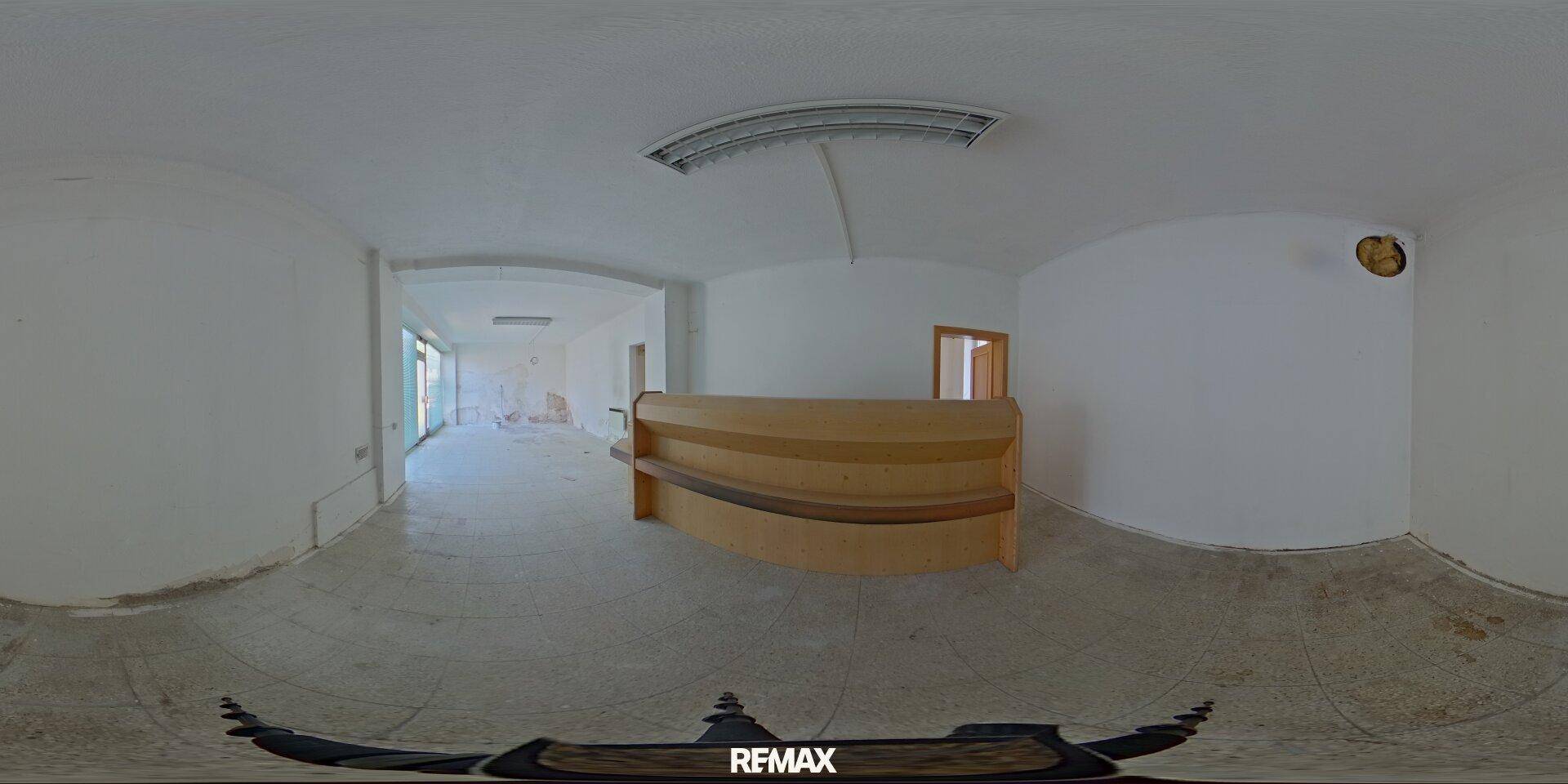 Panoramablick auf einen großen Geschäftsraum mit Holztresen und weißen Wänden.
