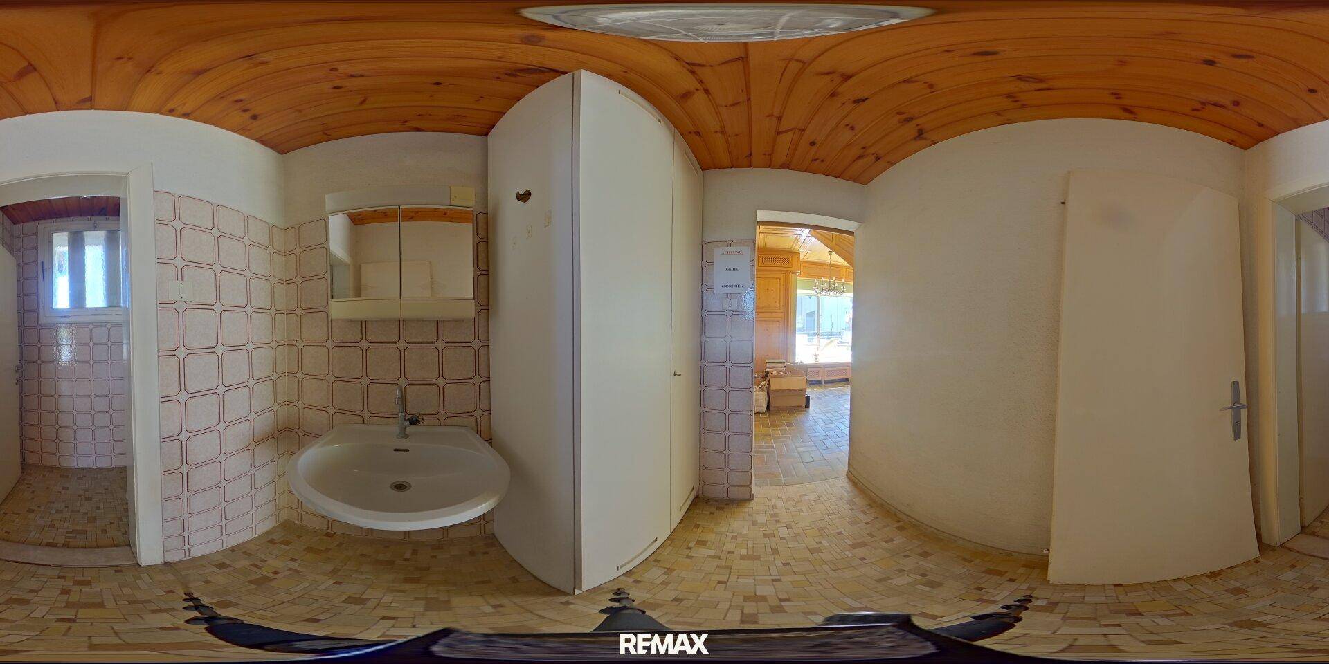 Panoramablick auf ein Badezimmer mit Waschbecken, Spiegel und Fliesenwänden.