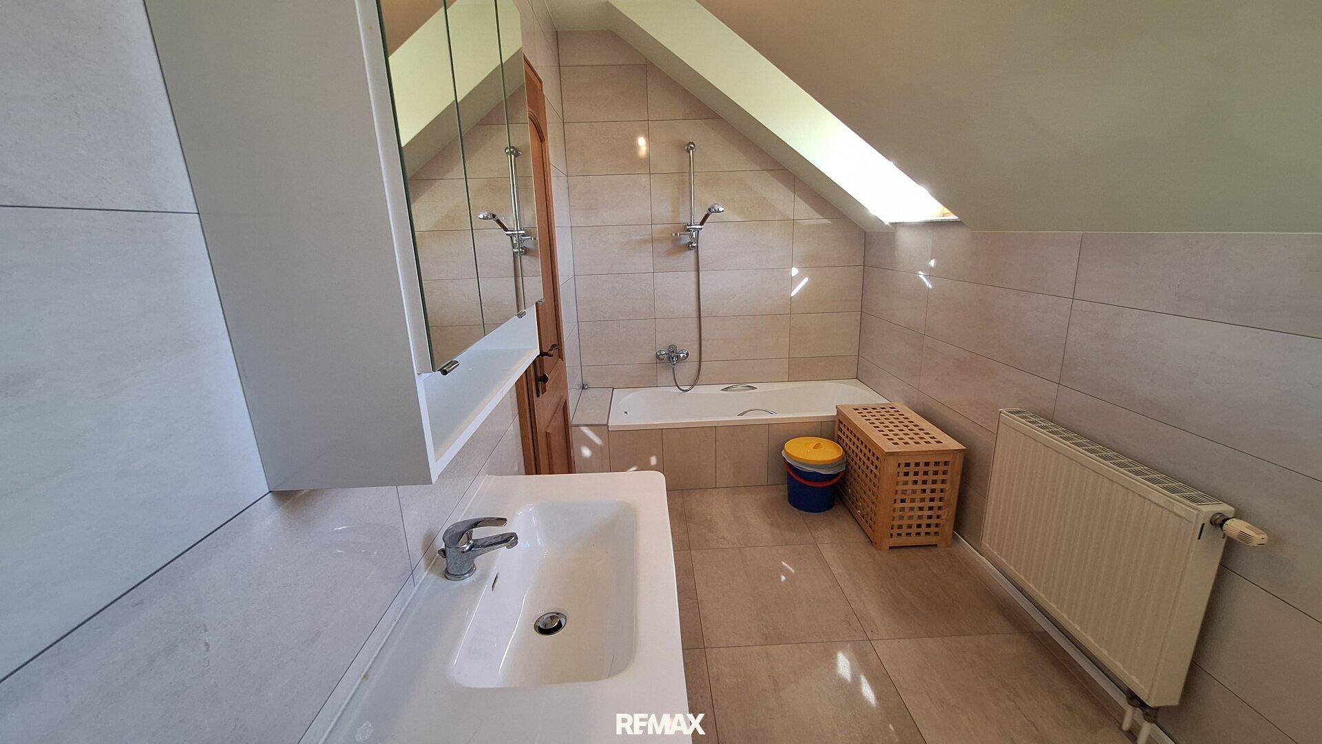 Helles Badezimmer im Dachgeschoss mit Badewanne, Waschbecken und Dachschräge.