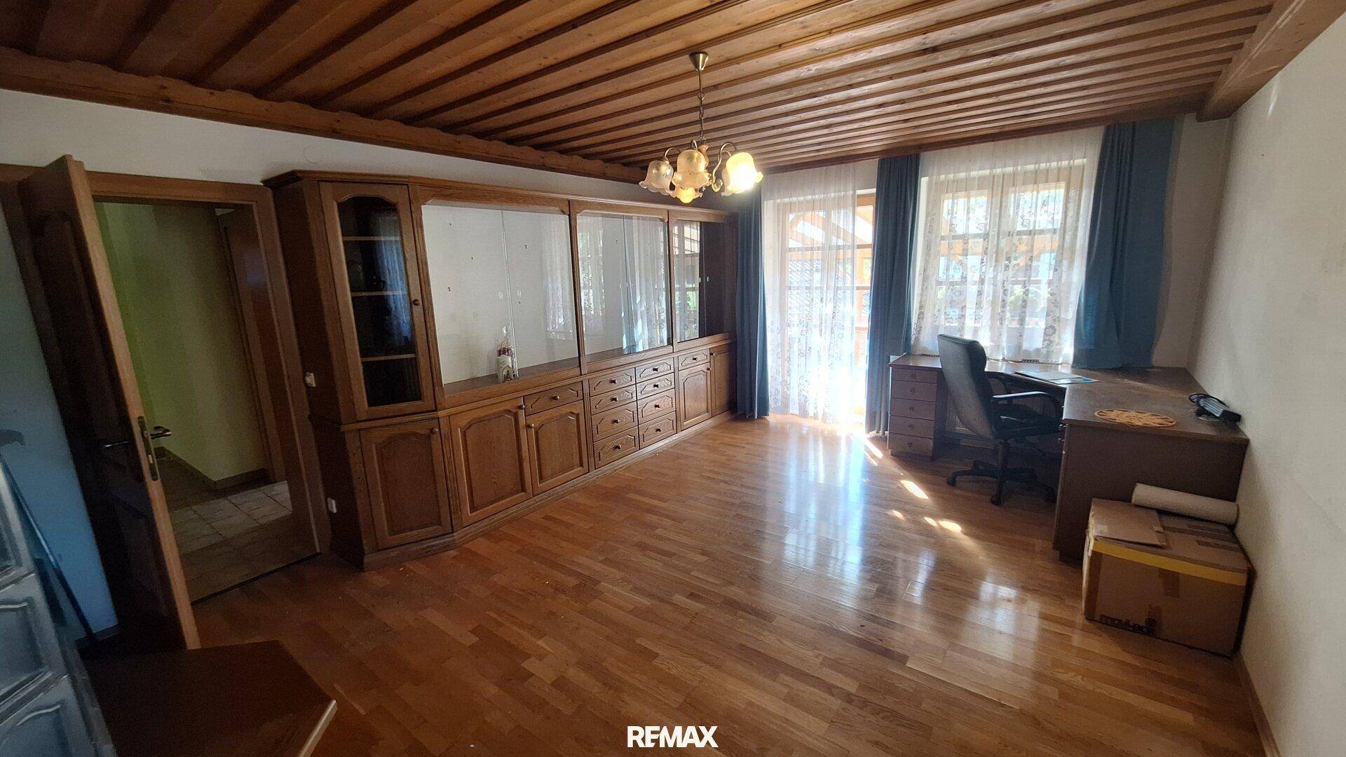 Geräumiges Wohnzimmer mit Holzboden, Holzdecke und traditionellen Holzmöbeln.