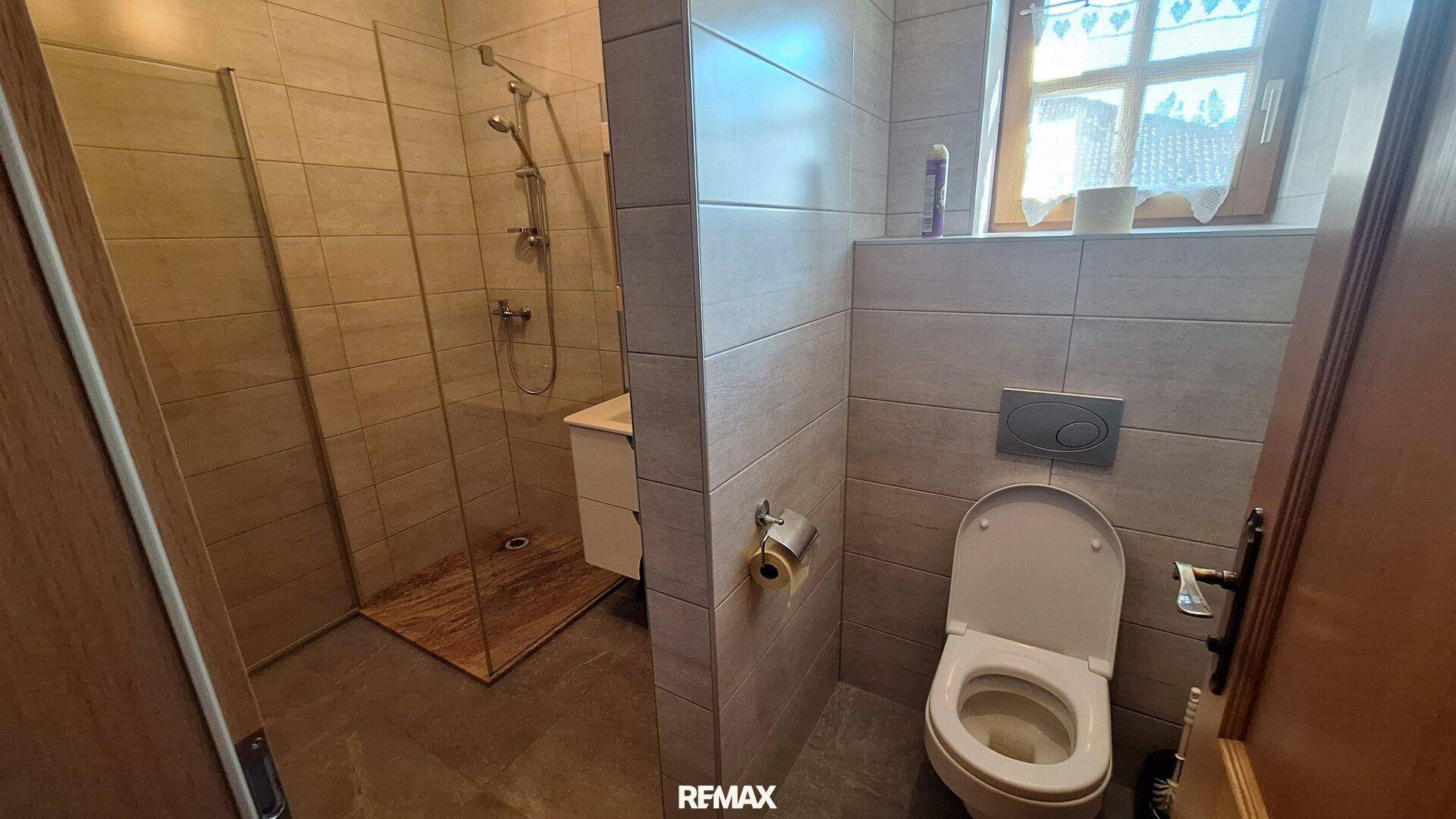 Modernes Badezimmer mit begehbarer Dusche, Wand-WC und hellen Fliesen.