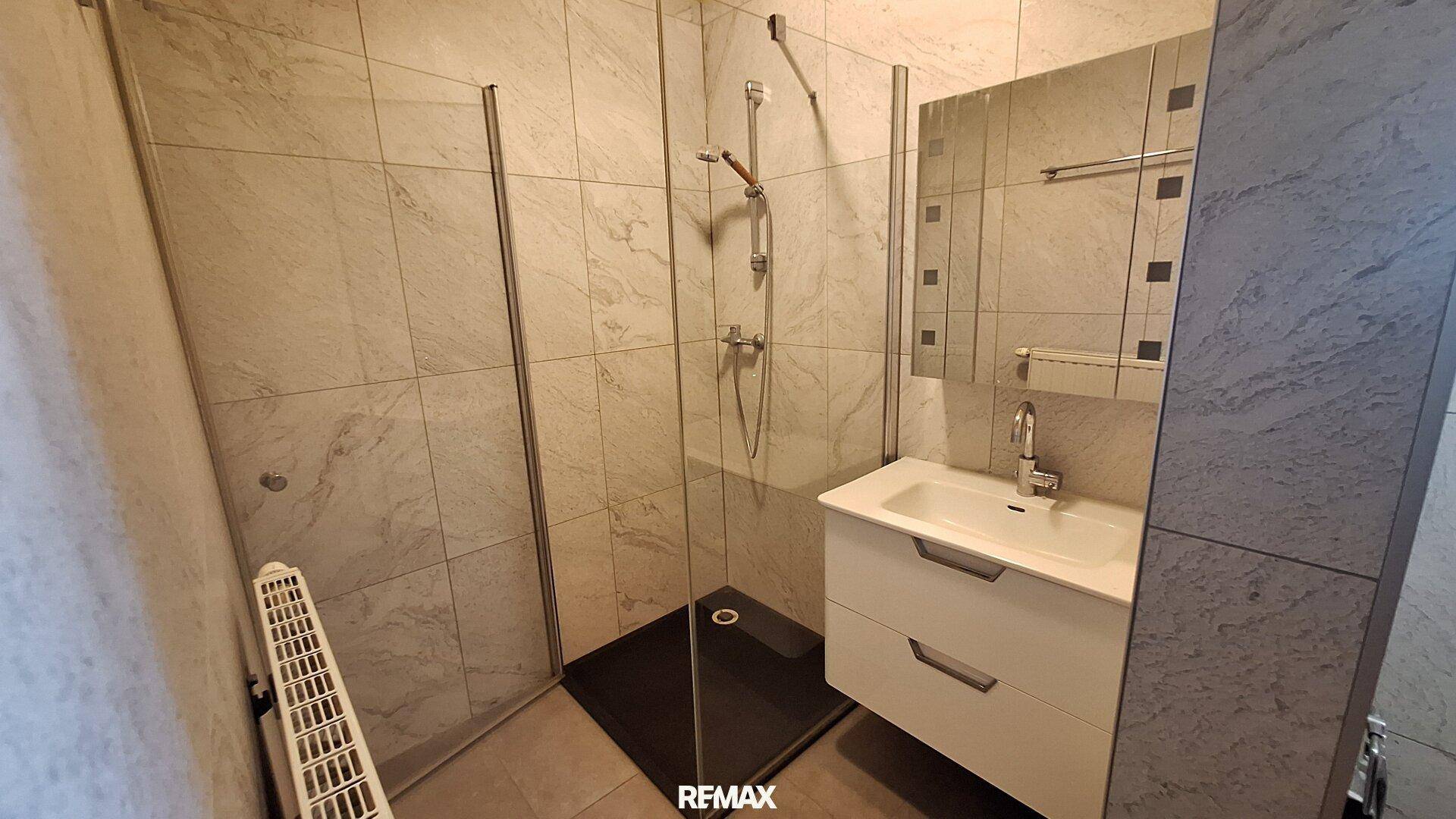 Helles Badezimmer mit moderner Dusche, Waschbecken und Spiegelschrank.